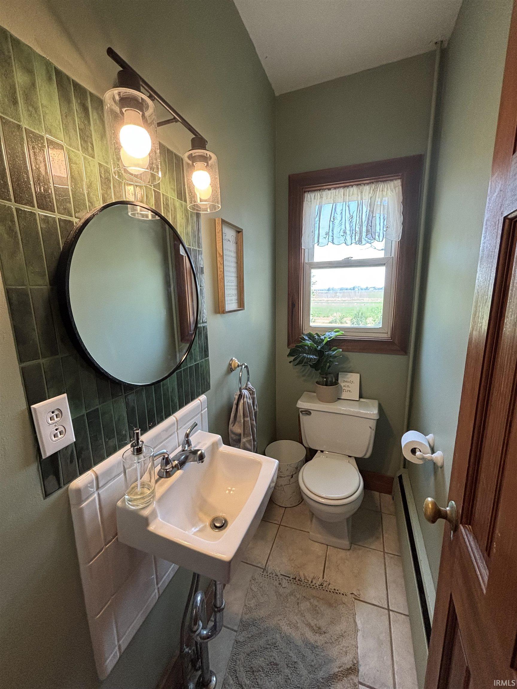 Pedestal sink with chrome fixtures, complemented by subway tile backsplash
