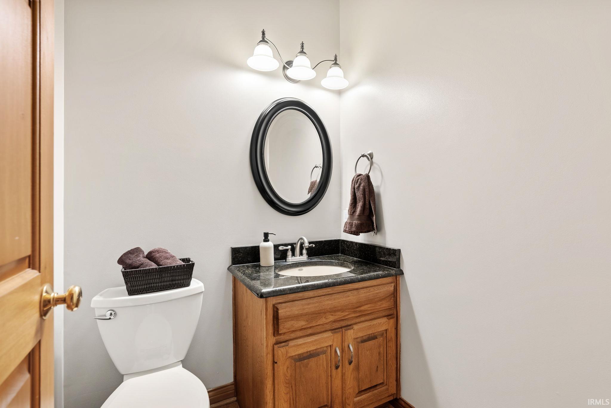Wood-finish vanity with a dark countertop and integrated sink basin