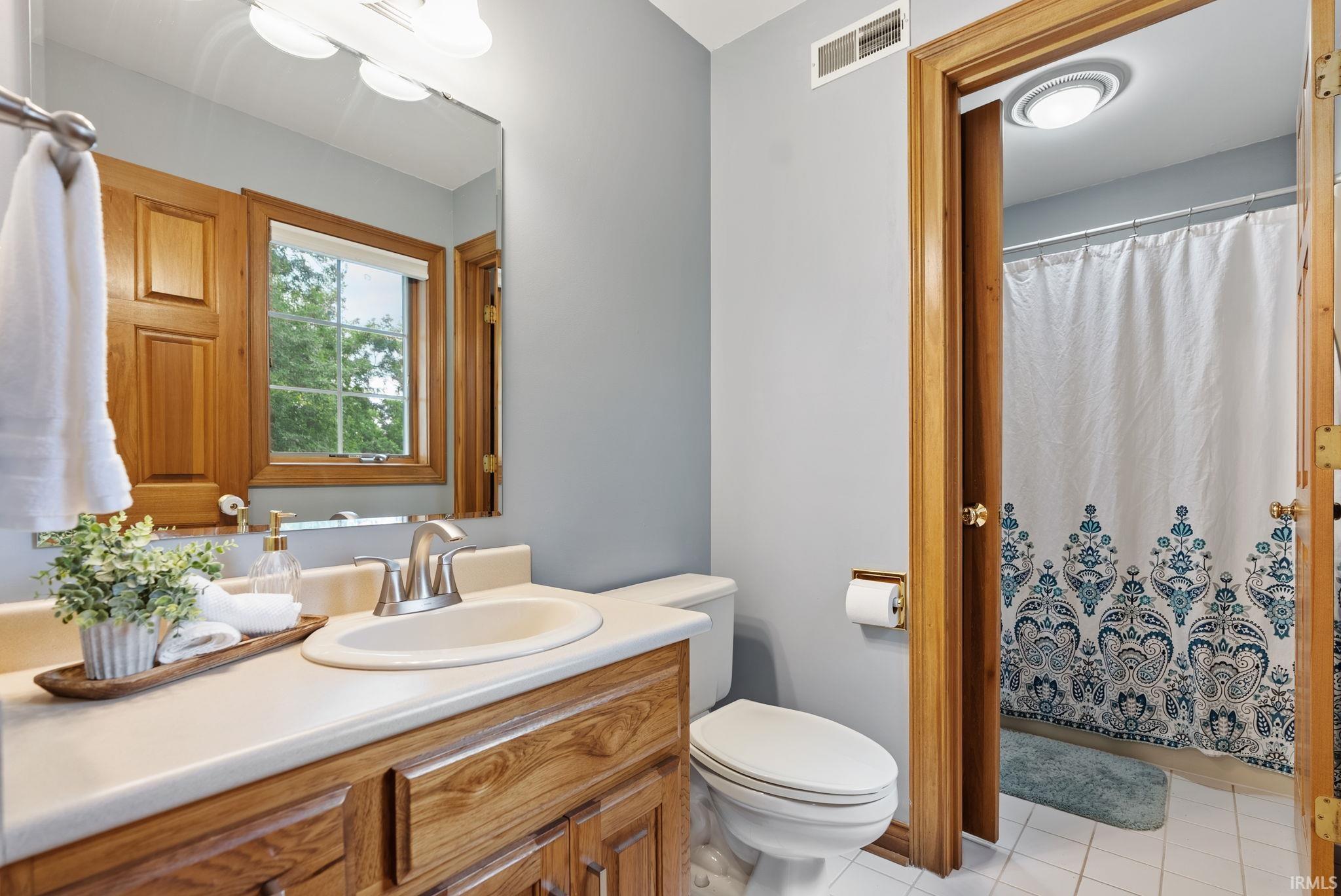 Bathroom featuring a single vanity with wood cabinetry and a light-colored countertop