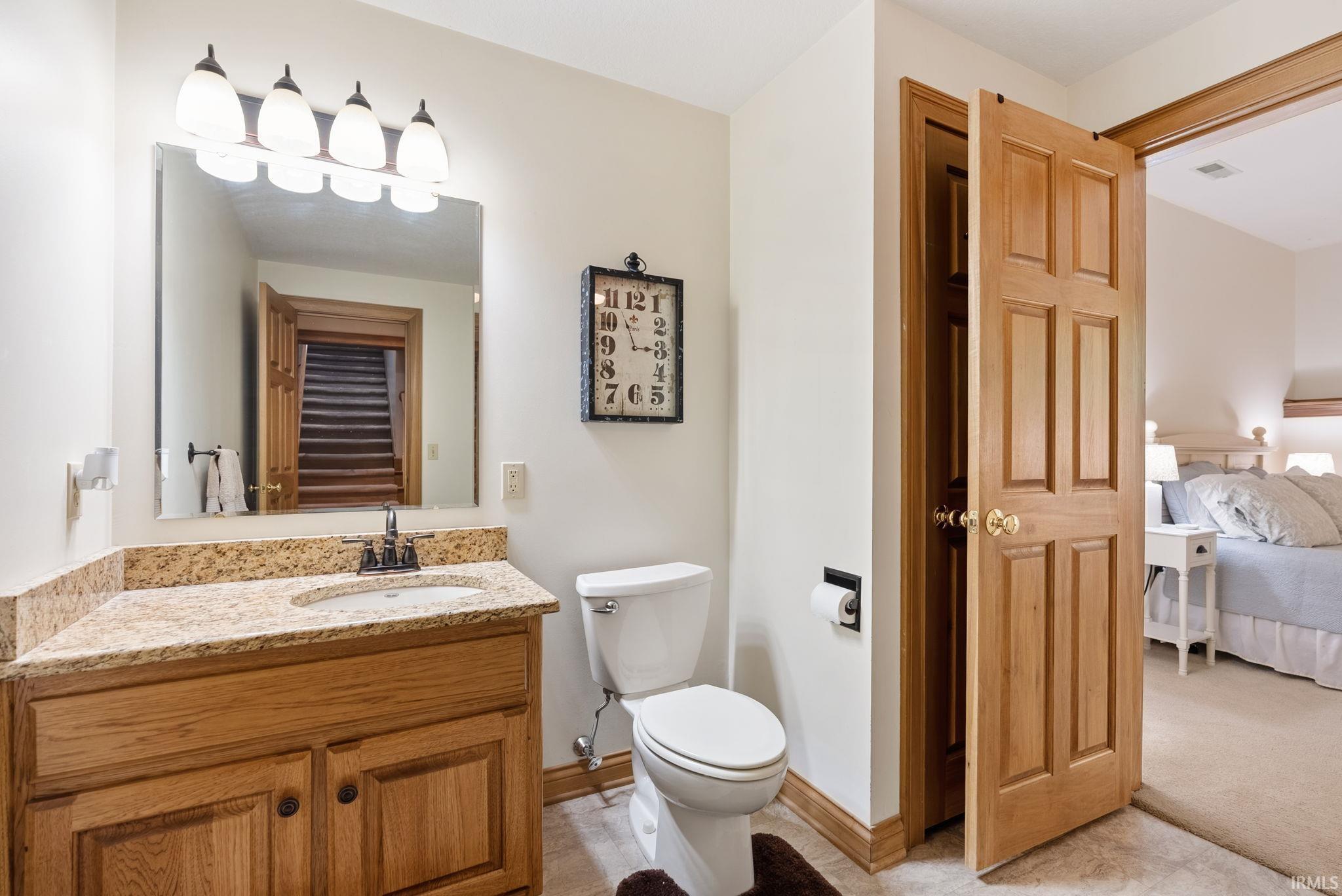 Bathroom featuring a light wood vanity with a stone countertop and an undermount sink