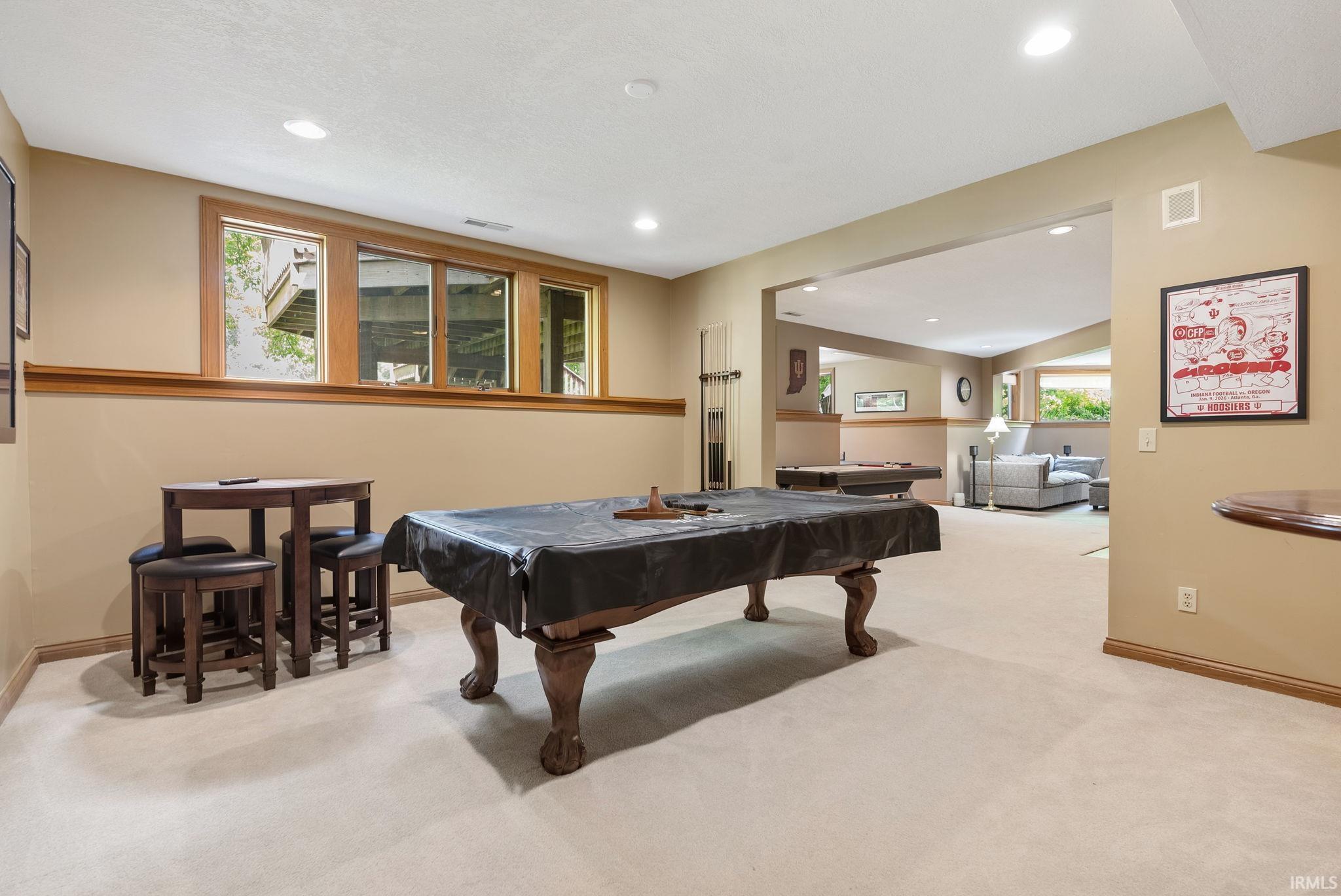 Spacious lower-level entertainment area featuring recessed lighting, light-toned carpeting, and a wood-framed window bank