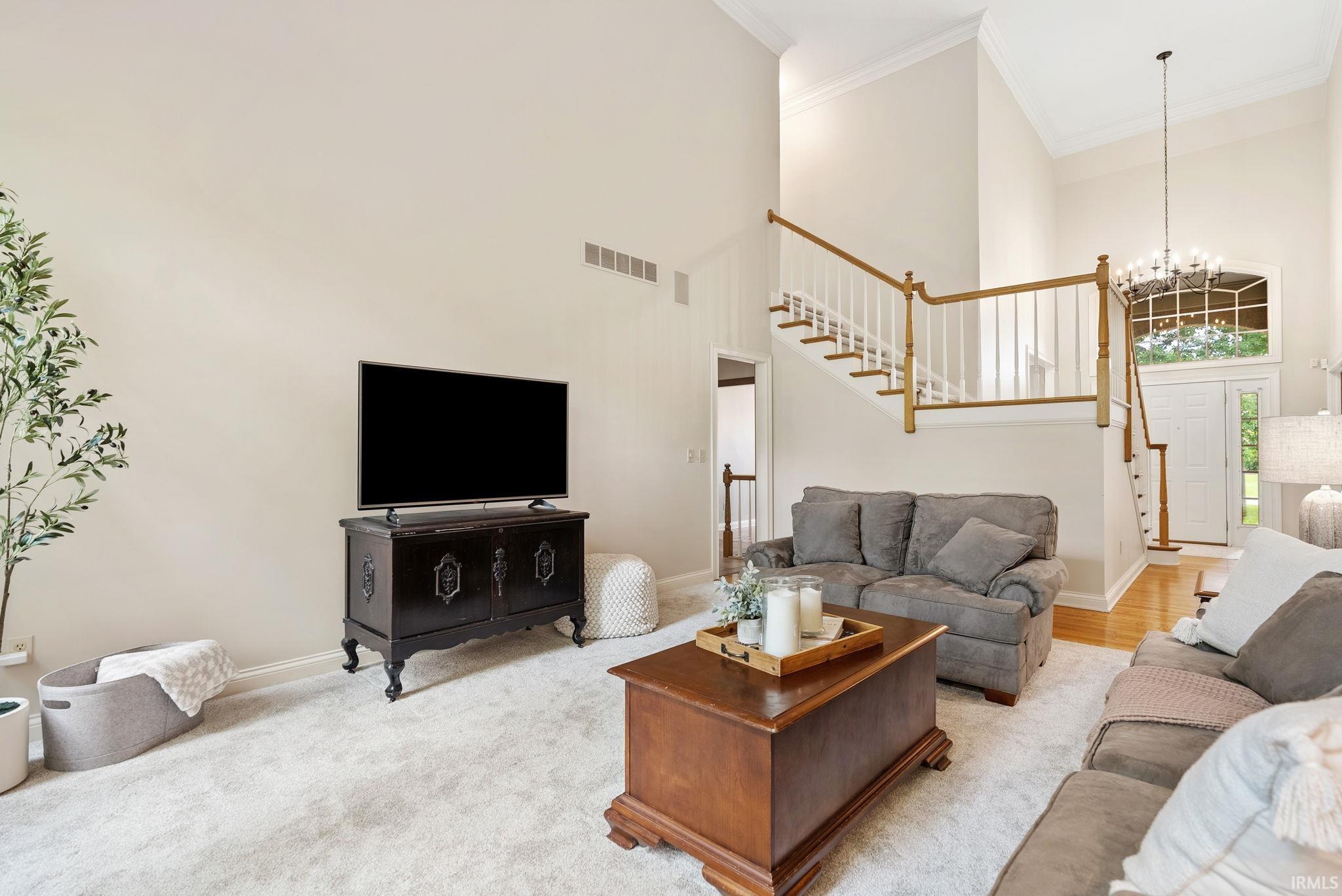 Two-story living area featuring a vaulted ceiling and a grand staircase with white spindles and wood handrails