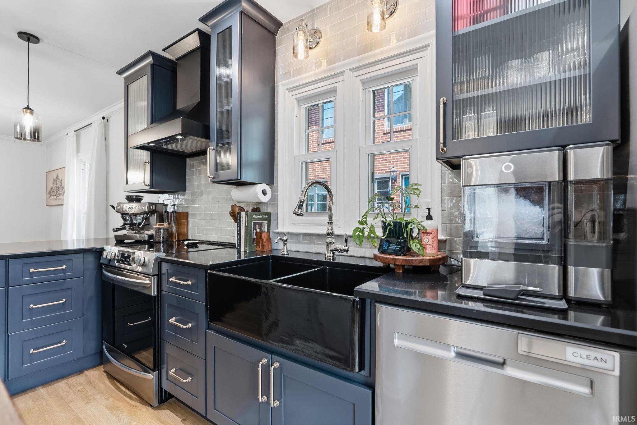 Kitchen featuring dark blue cabinetry with polished hardware, black countertops, and a white subway tile backsplash