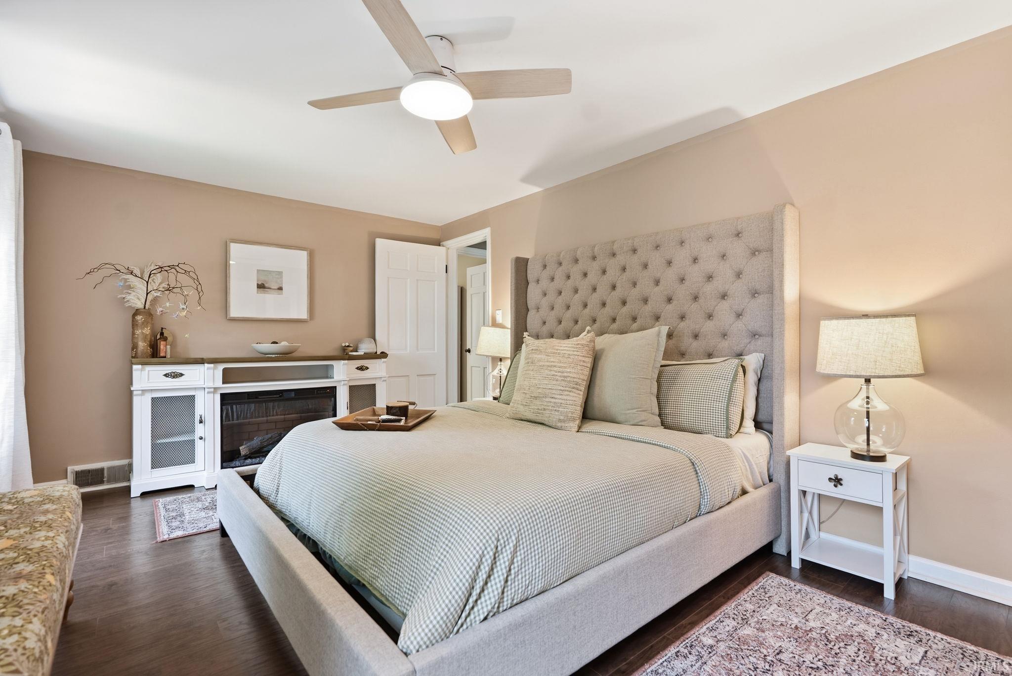 Spacious room featuring wood-finish flooring, a ceiling fan with integrated lighting, and neutral wall tones