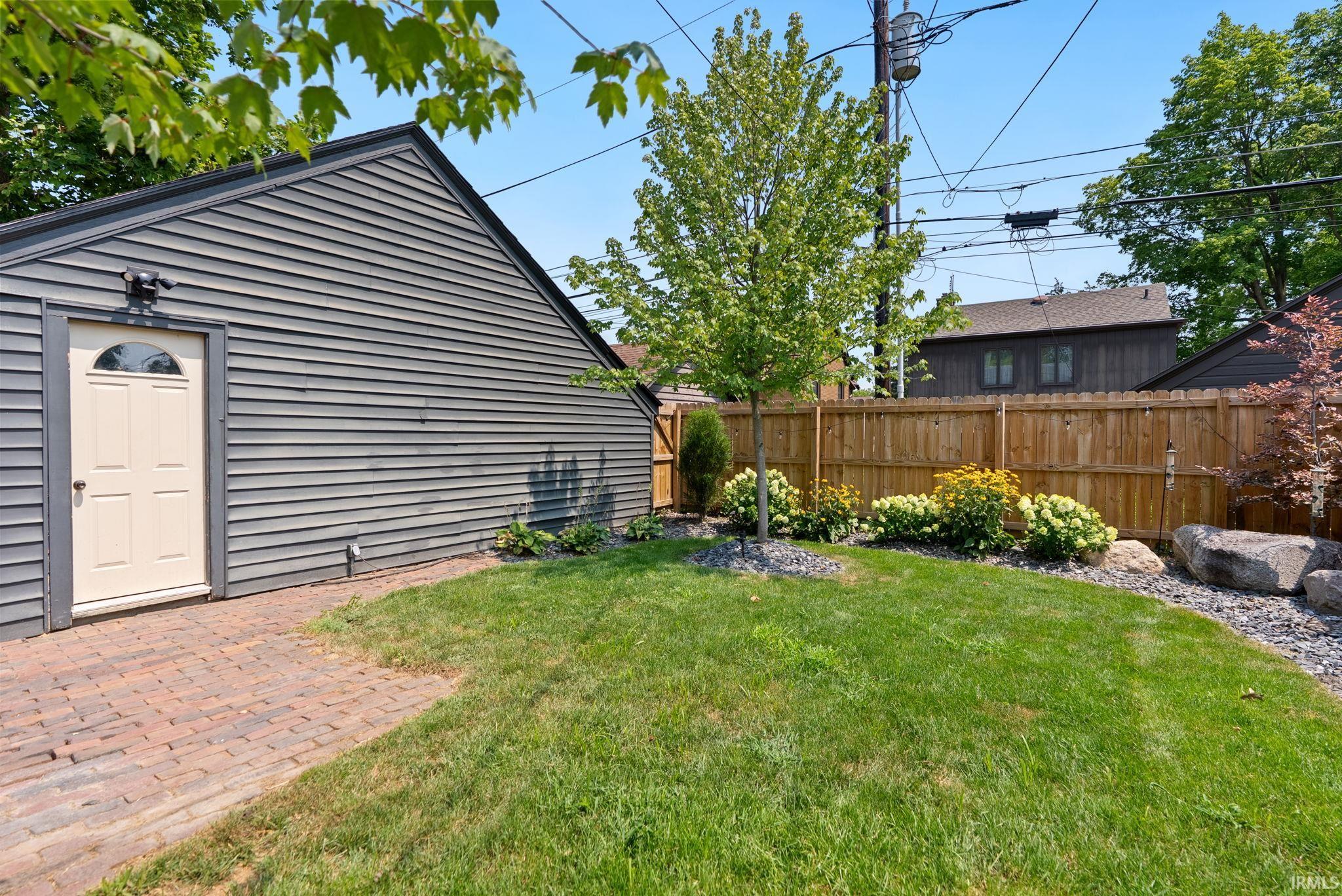 Expansive backyard featuring a manicured lawn, established plantings, and a wood privacy fence