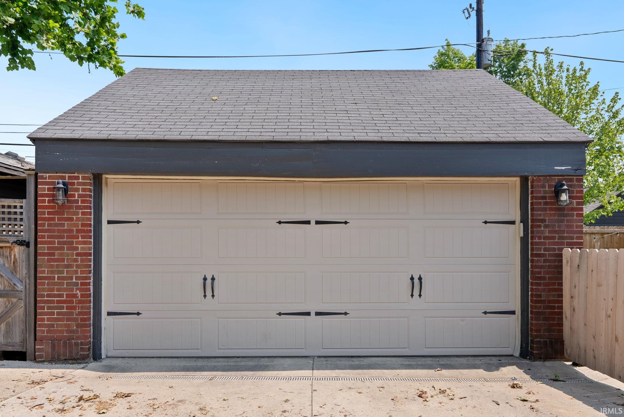 Two-car garage featuring a light-colored panel door with decorative hardware