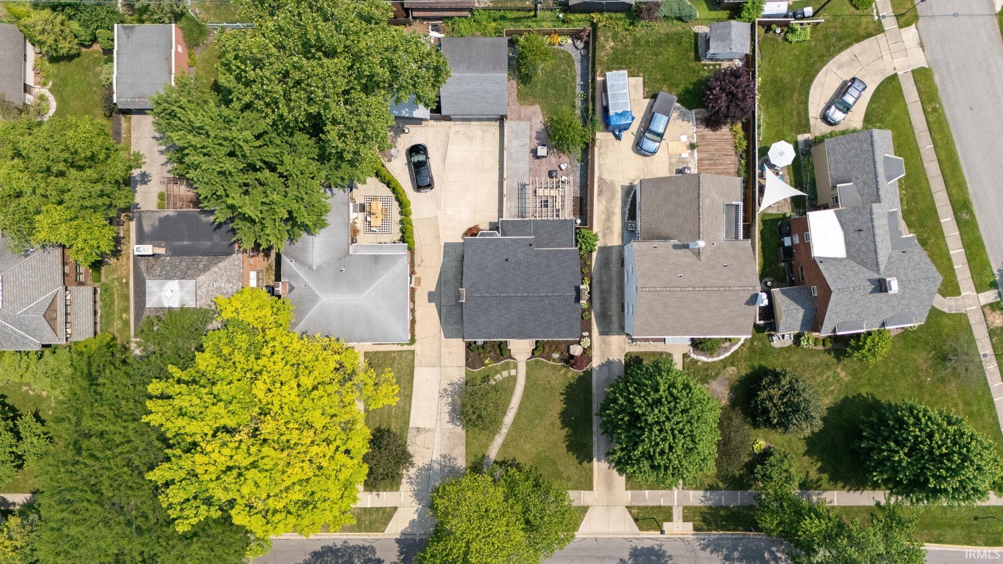 Overhead aerial presenting a residential street with mature trees and paved sidewalks