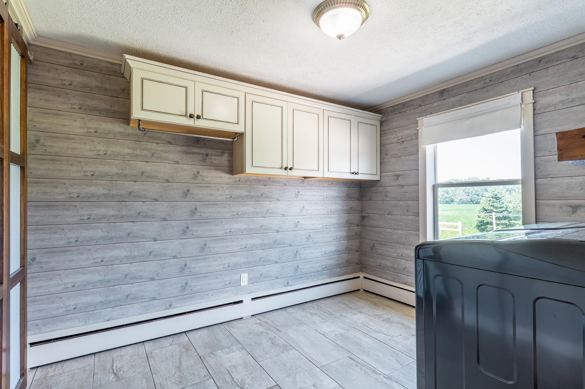 Laundry area with plank-style wall treatment and wood-finish flooring