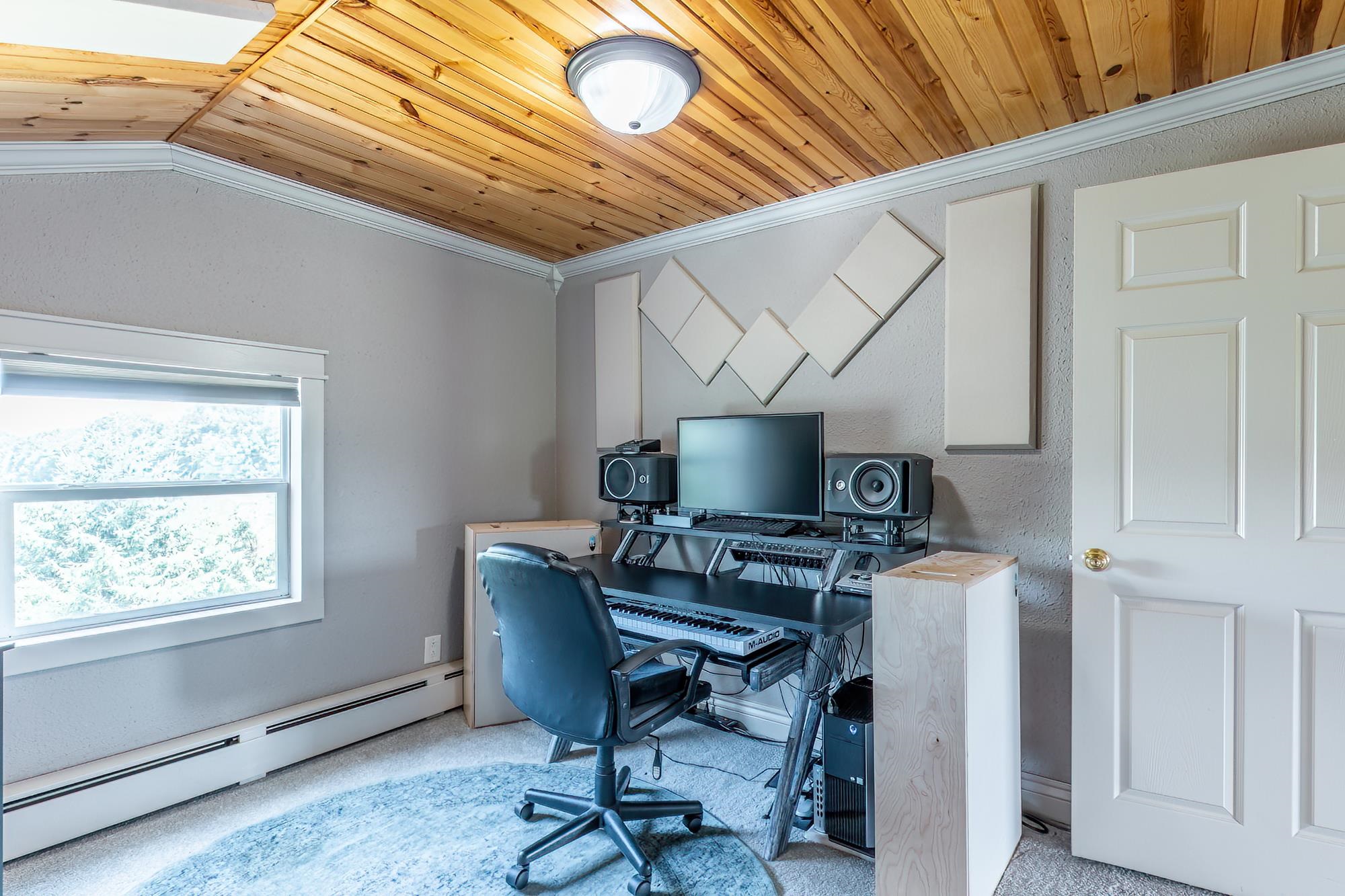 Room featuring a wood-panel ceiling, neutral wall color, and a multi-pane window
