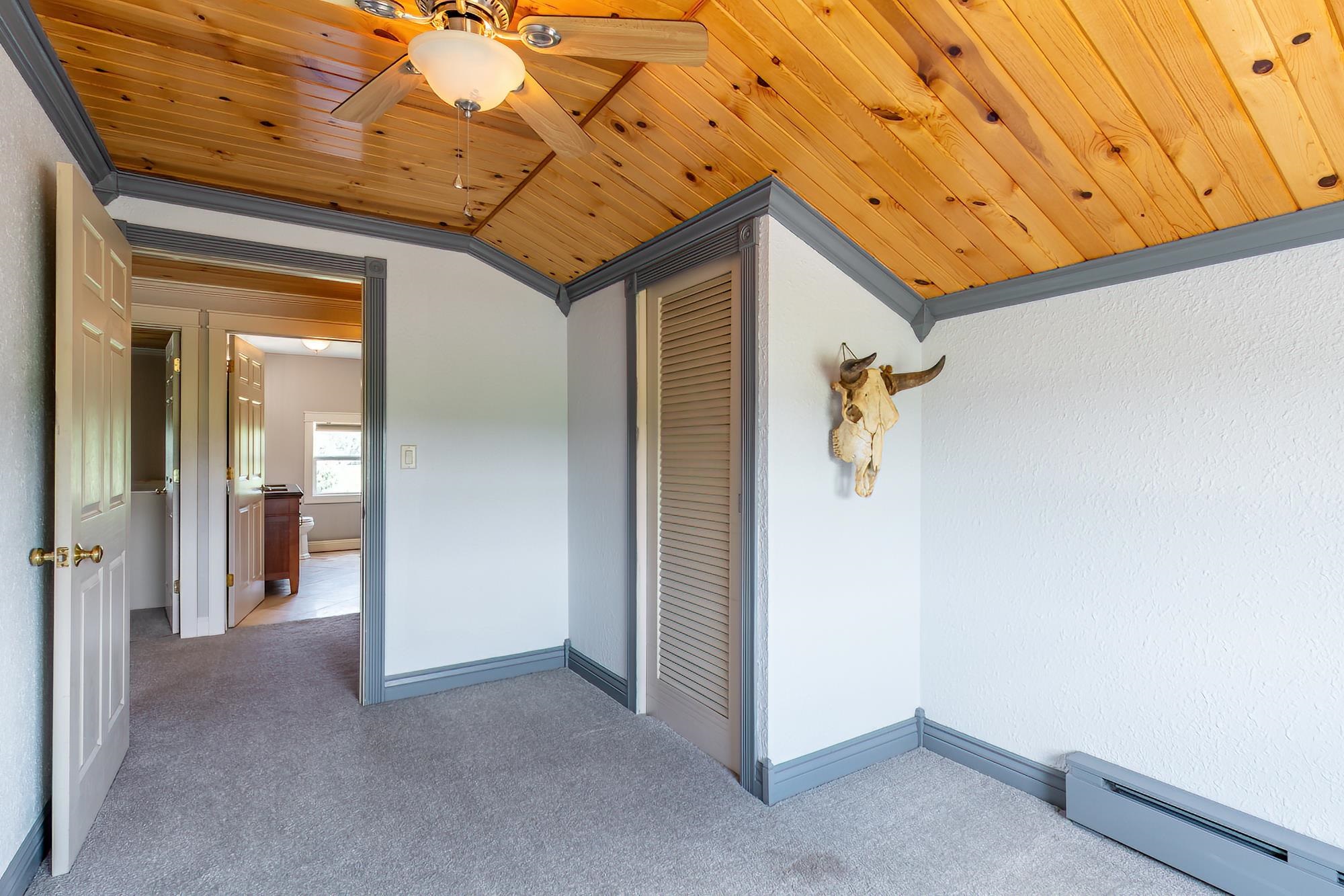 Room featuring a wood-panel ceiling, gray trim, and textured white walls