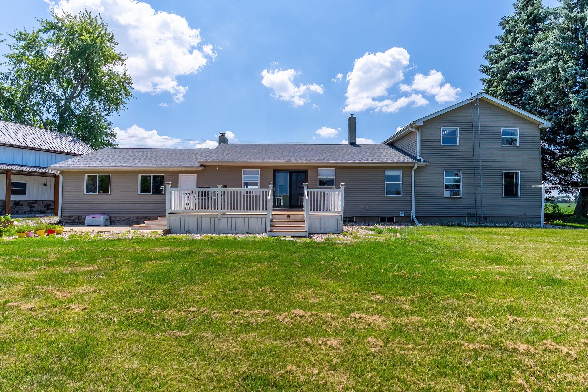 Rear elevation featuring a multi-level deck with white railings, a tan siding exterior, and a dark shingle roof