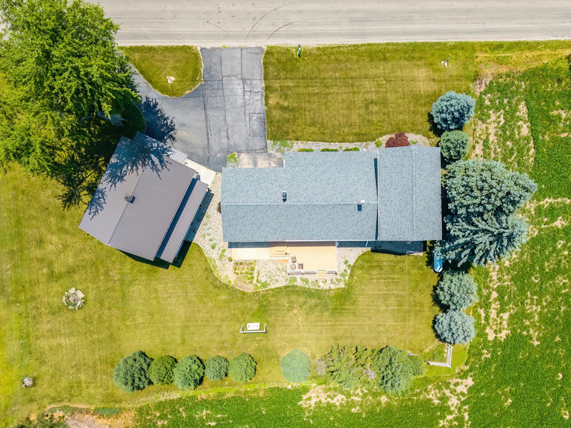 Property featuring a main residence with a gray shingle roof, an adjacent structure with a dark metal roof, and a paved driveway