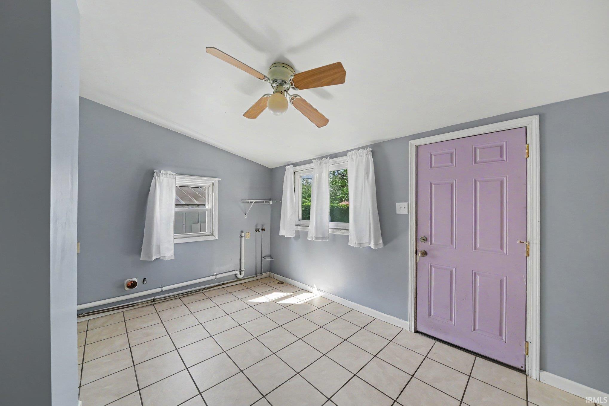 Room featuring ceramic tile flooring, a sloped ceiling, and multiple windows
