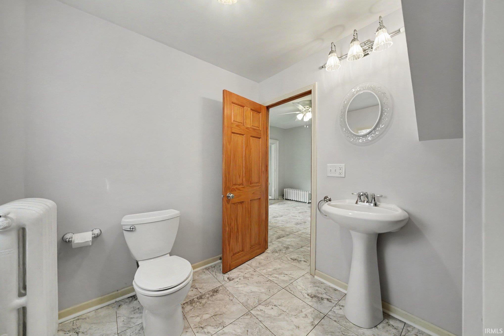 Bathroom featuring a pedestal sink, white toilet, and tile flooring