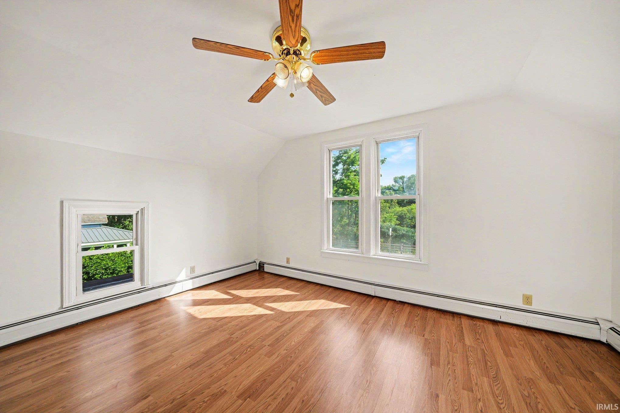 Room featuring wood-finish flooring, a ceiling fan with integrated lighting, two double-hung windows, and a single-pane window