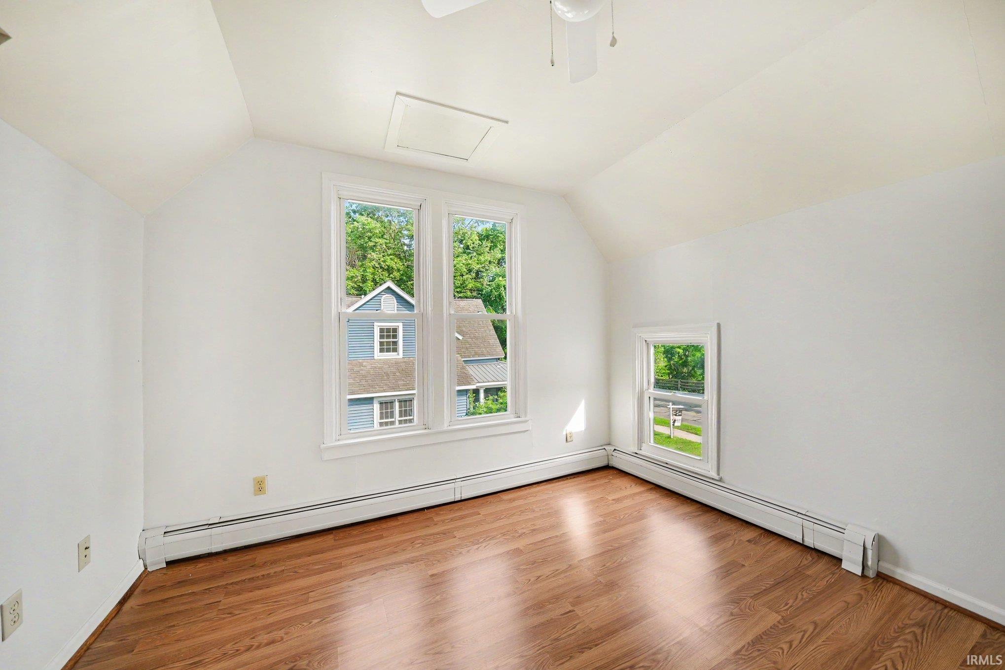 Bright interior space featuring wood-finish flooring, white painted walls, and multiple windows