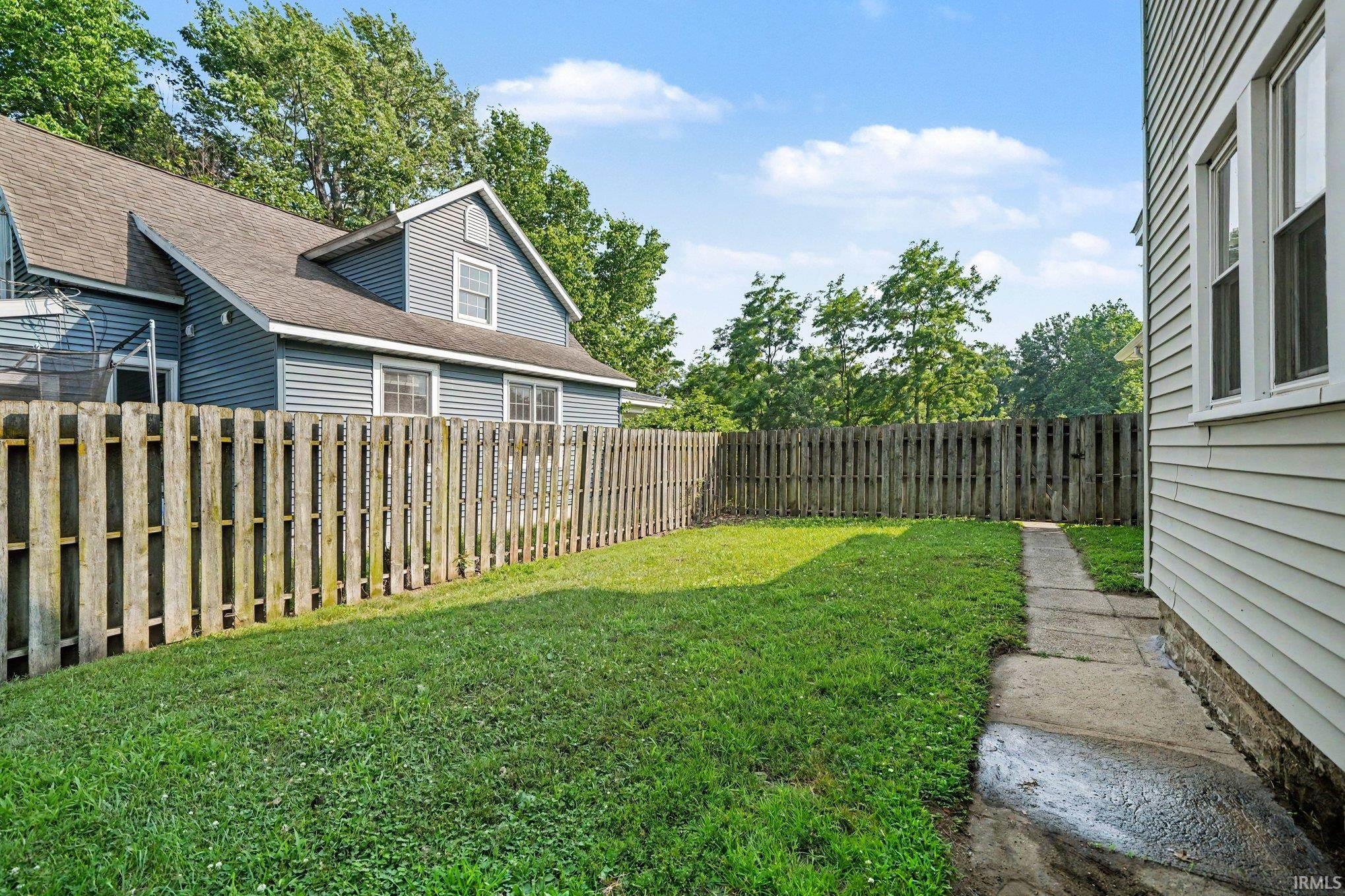 Enclosed grassy yard with a wooden privacy fence