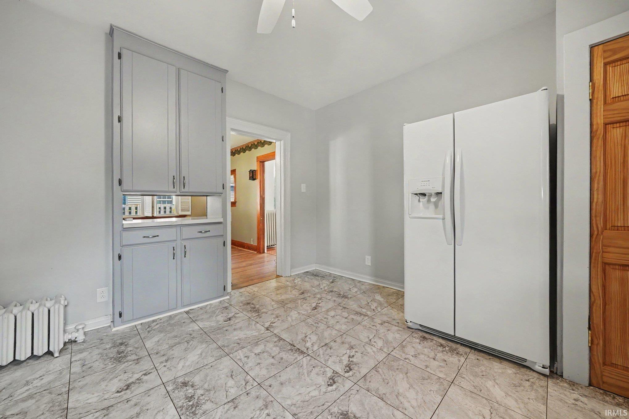 Kitchen area featuring tile flooring, a side-by-side refrigerator, built-in cabinetry with a countertop, and a ceiling fan