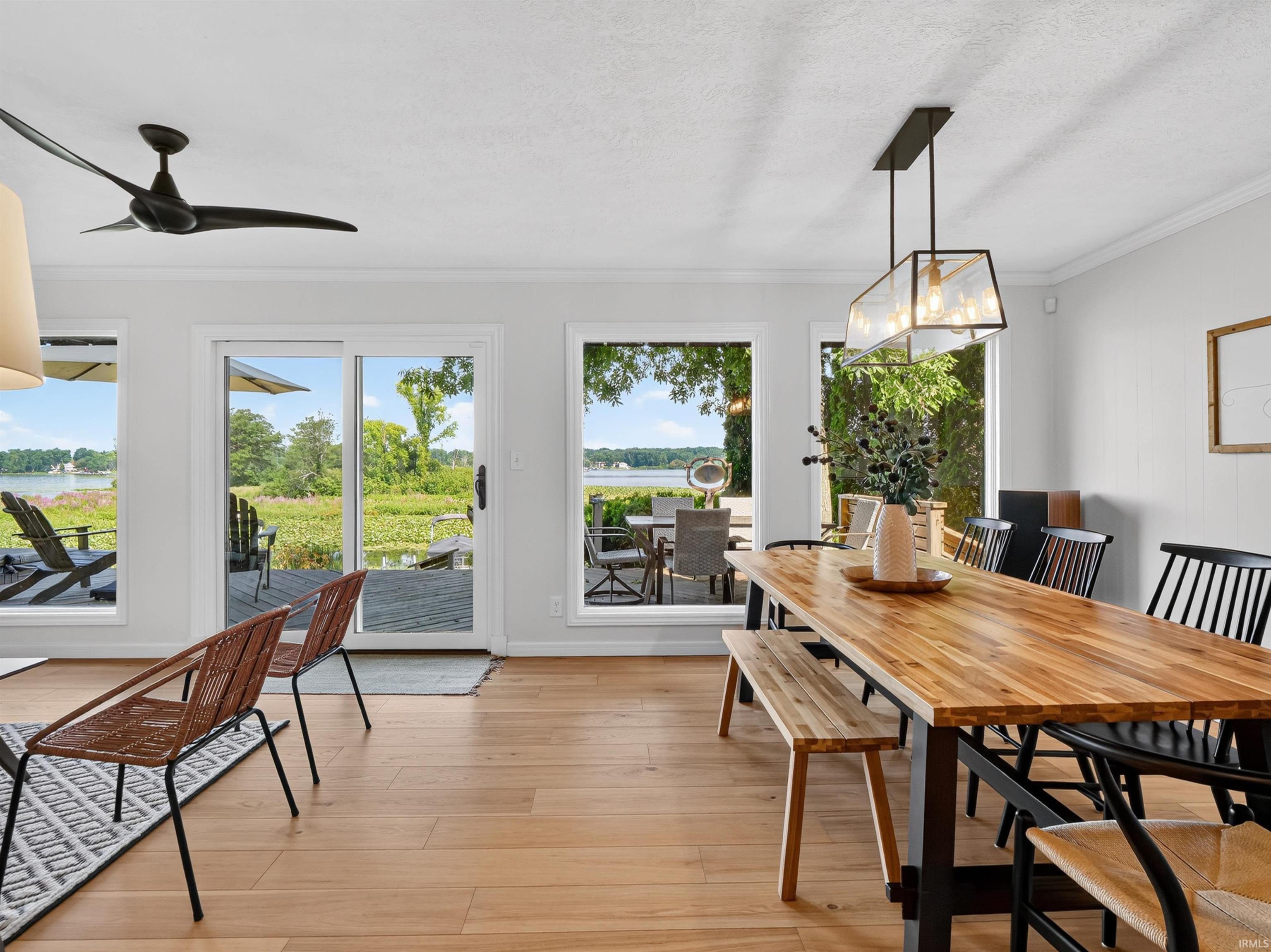 Expansive dining area featuring wood-finish flooring, a linear chandelier, and multiple windows