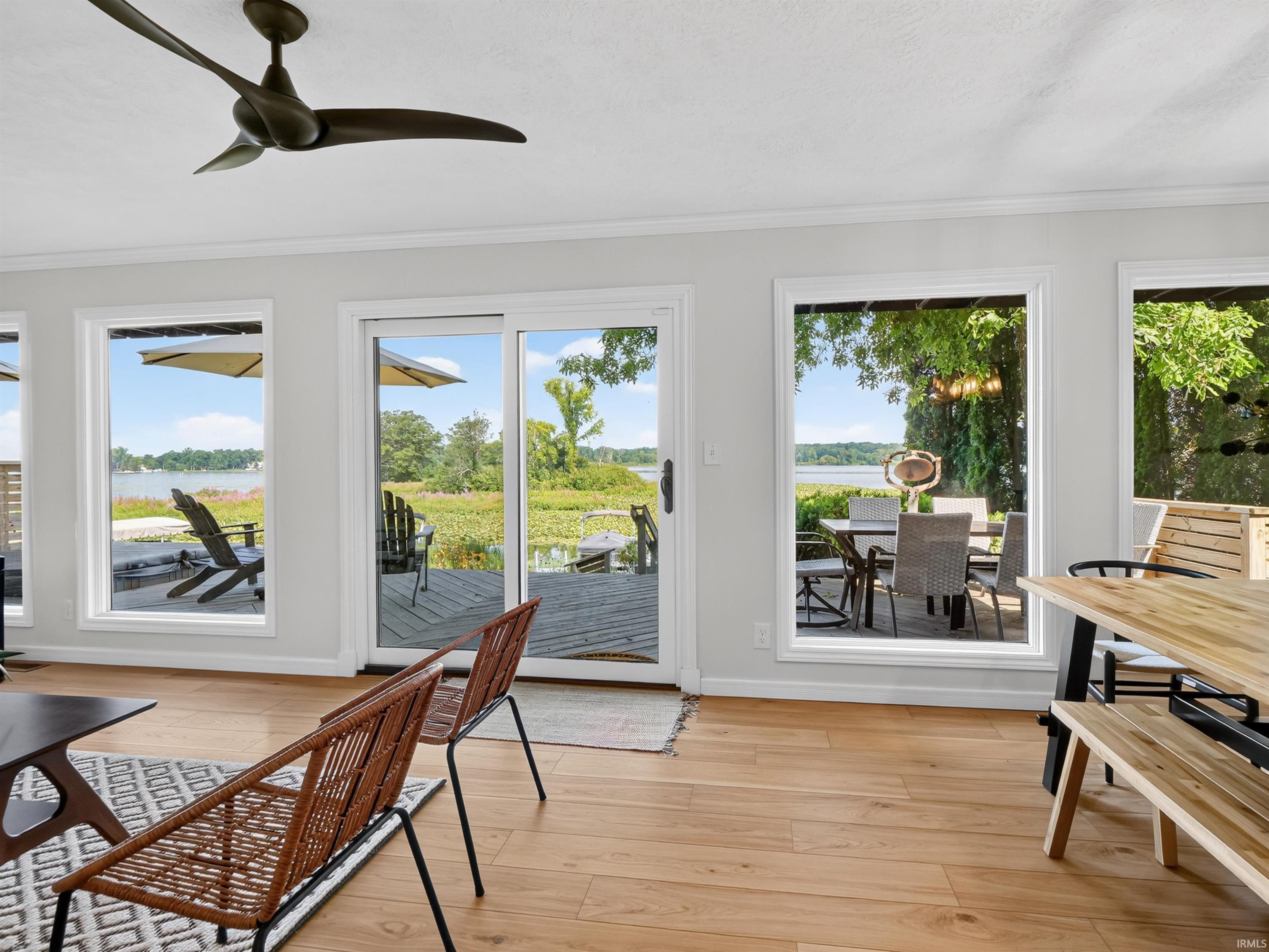 Waterfront setting with a spacious deck, multiple large windows, and a sliding glass door providing abundant natural light