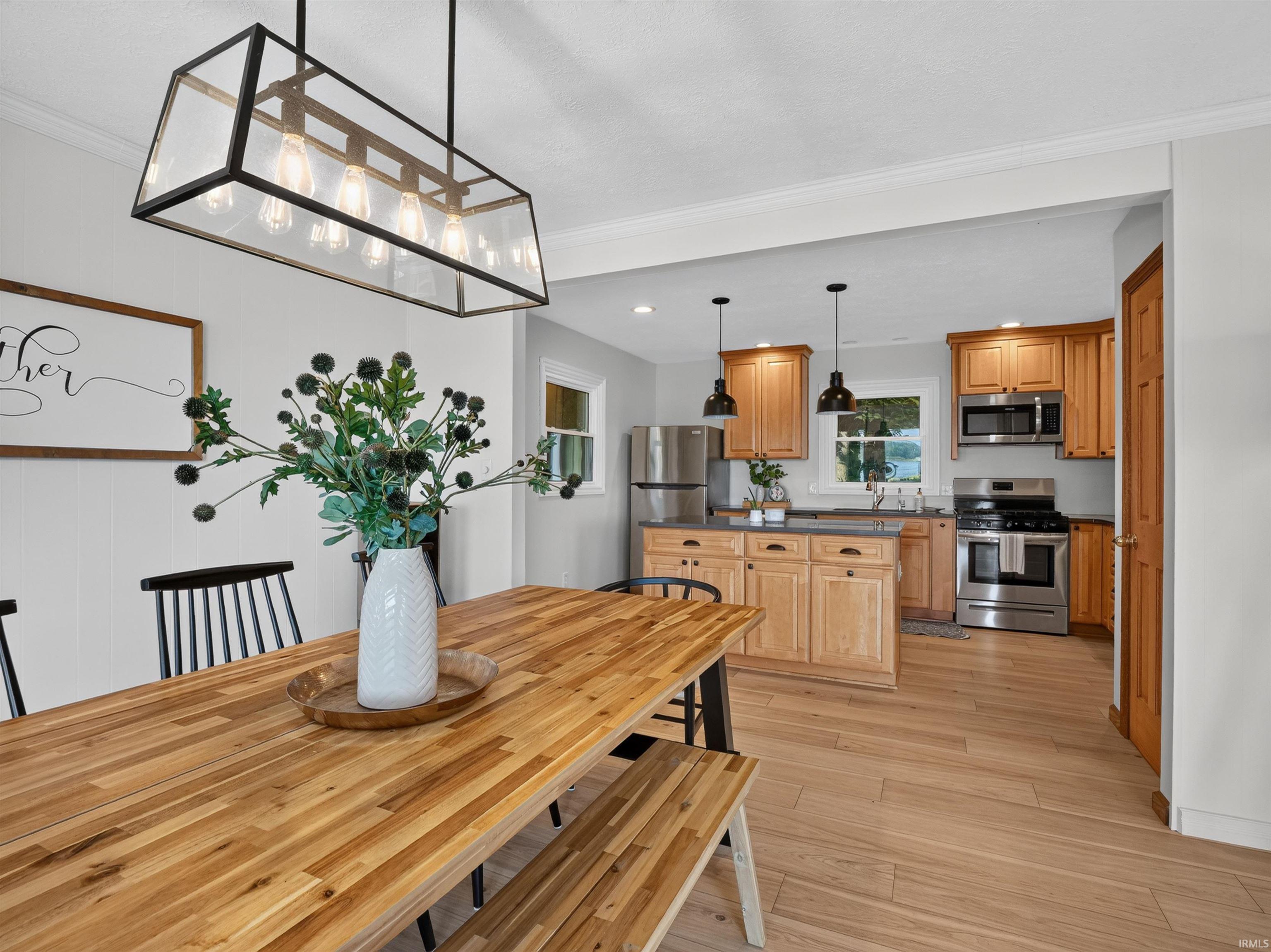 Dining area featuring a rectangular wood-finish table and seating, illuminated by a linear pendant light fixture