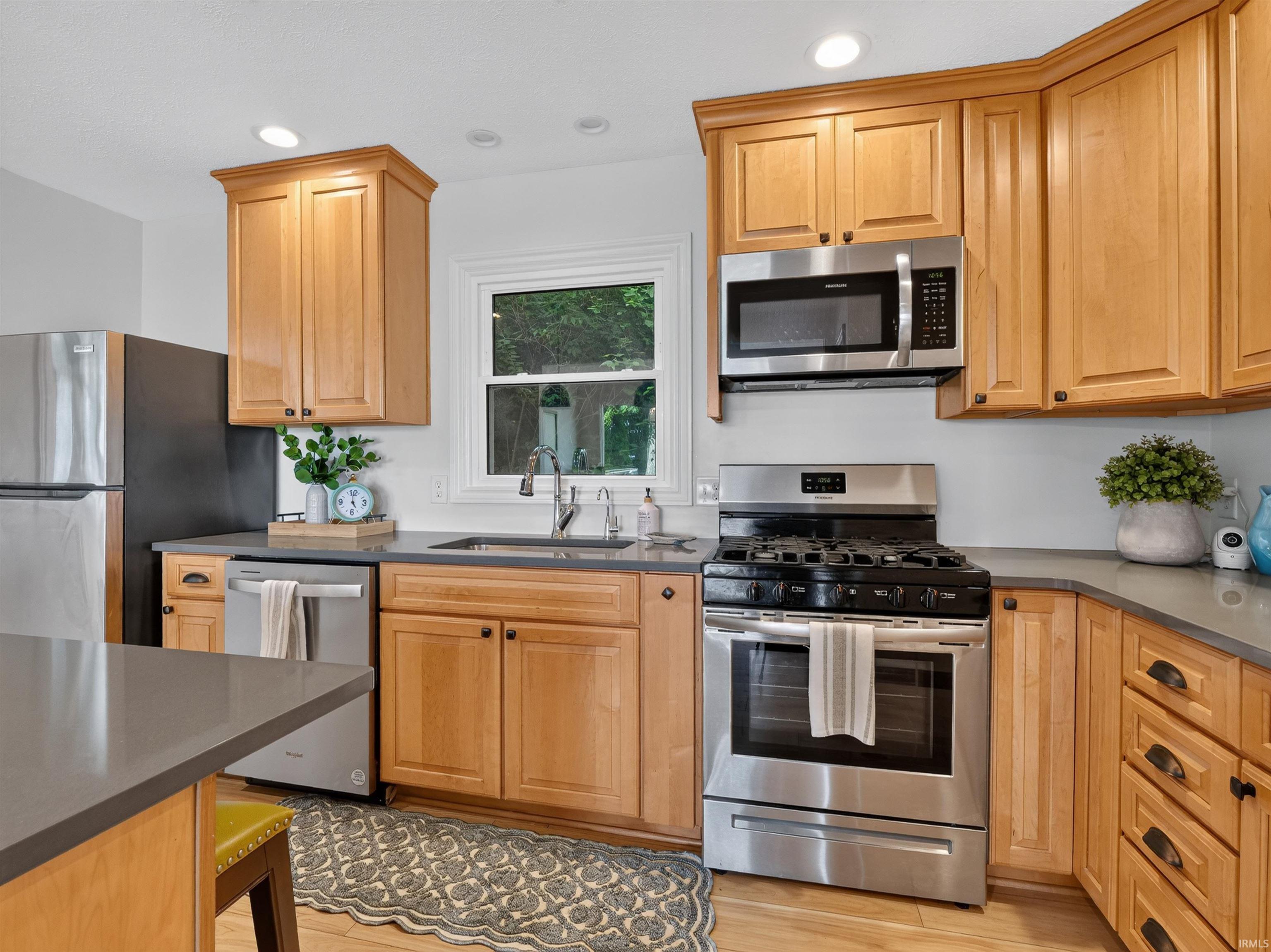 Kitchen featuring wood-finish cabinetry, stainless steel appliances, a double basin sink, and ample countertop space