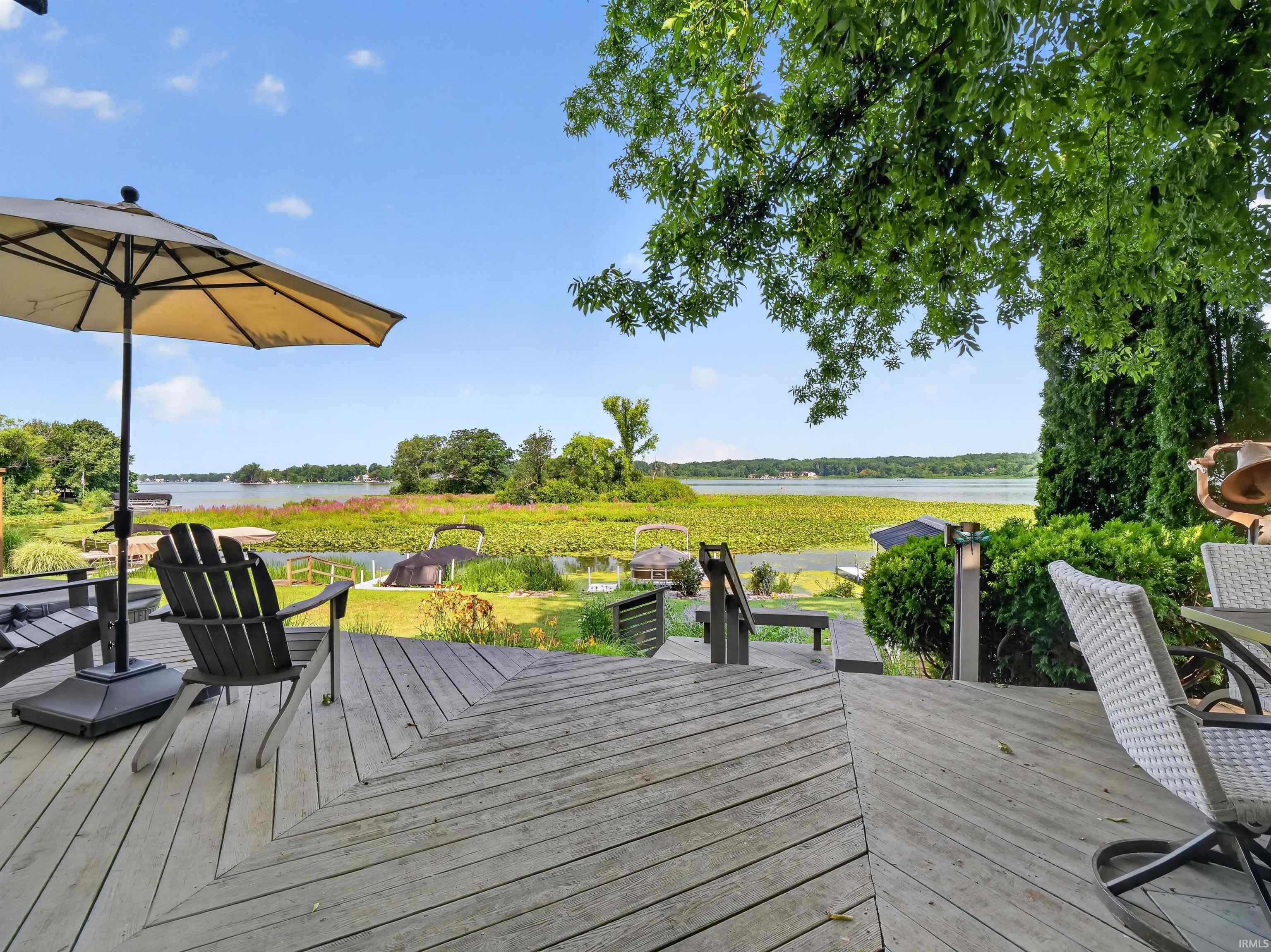 Expansive outdoor deck with a light wood-finish surface, featuring a built-in outdoor lighting fixture