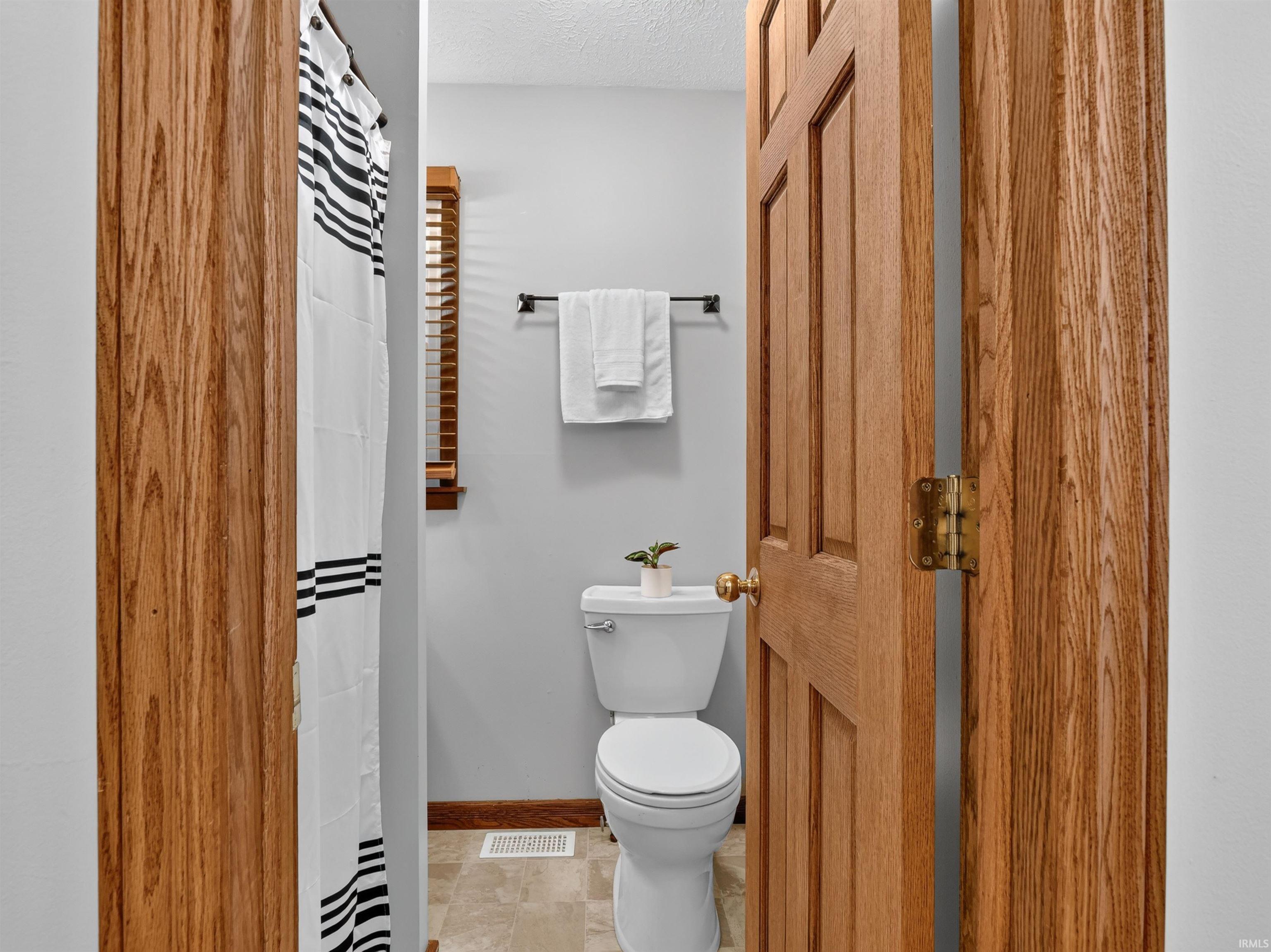 Bathroom featuring a white toilet, light gray walls, and wood-finish door and trim