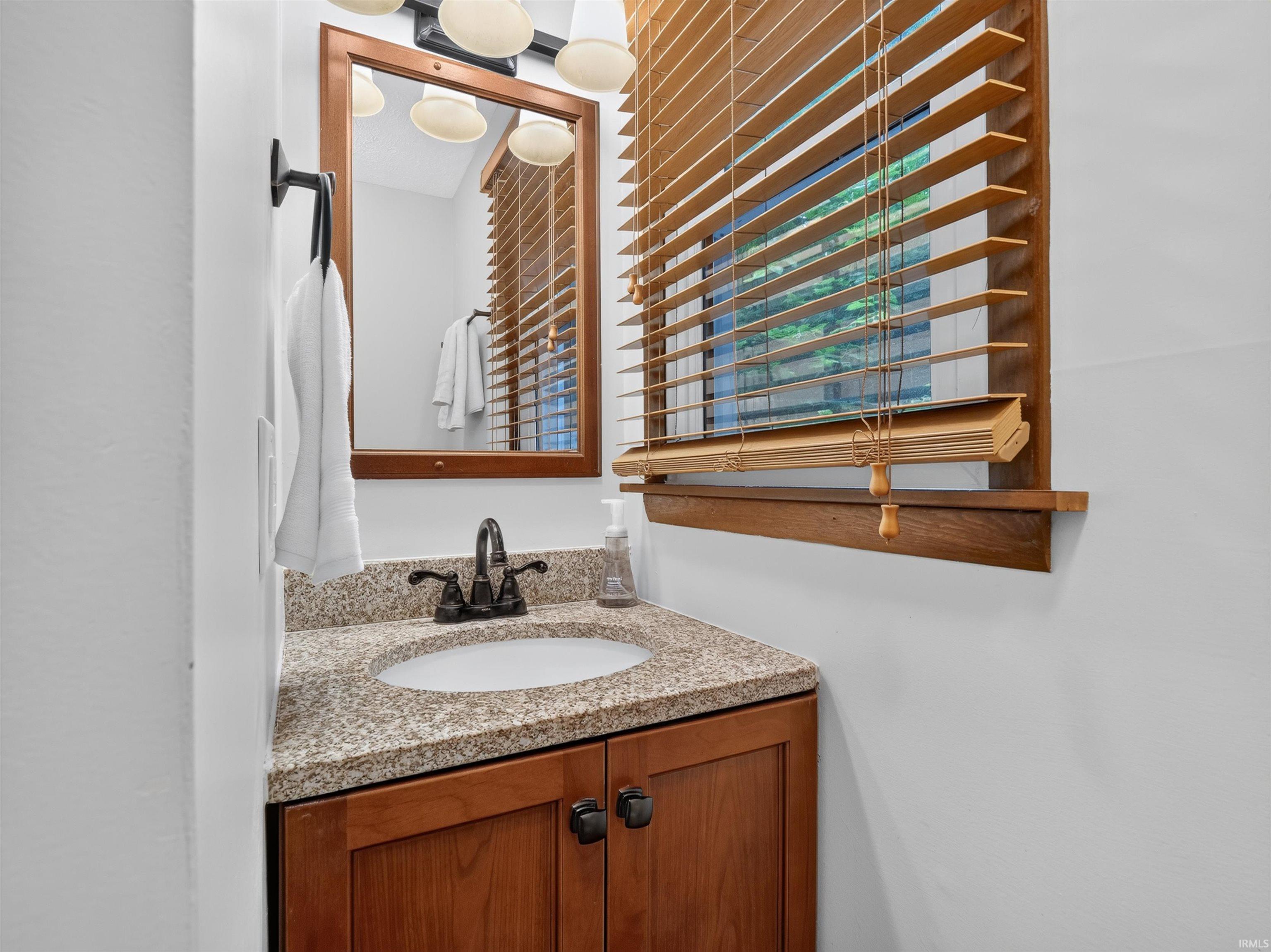 Vanity featuring a speckled countertop, a white oval undermount sink, and a dark bronze two-handle faucet