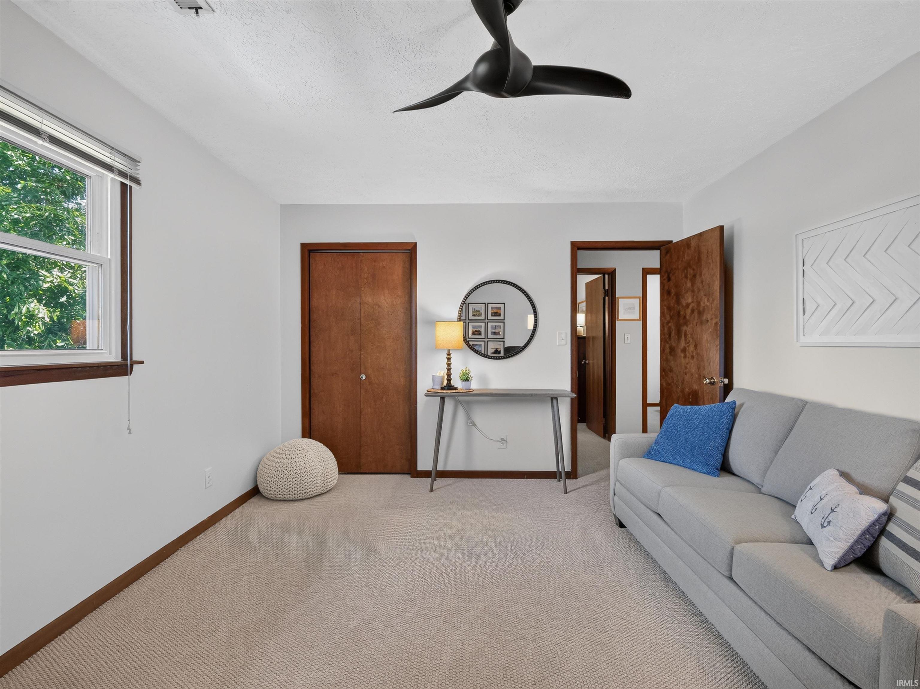 Neutral carpeted flooring with white walls and a matte black ceiling fan
