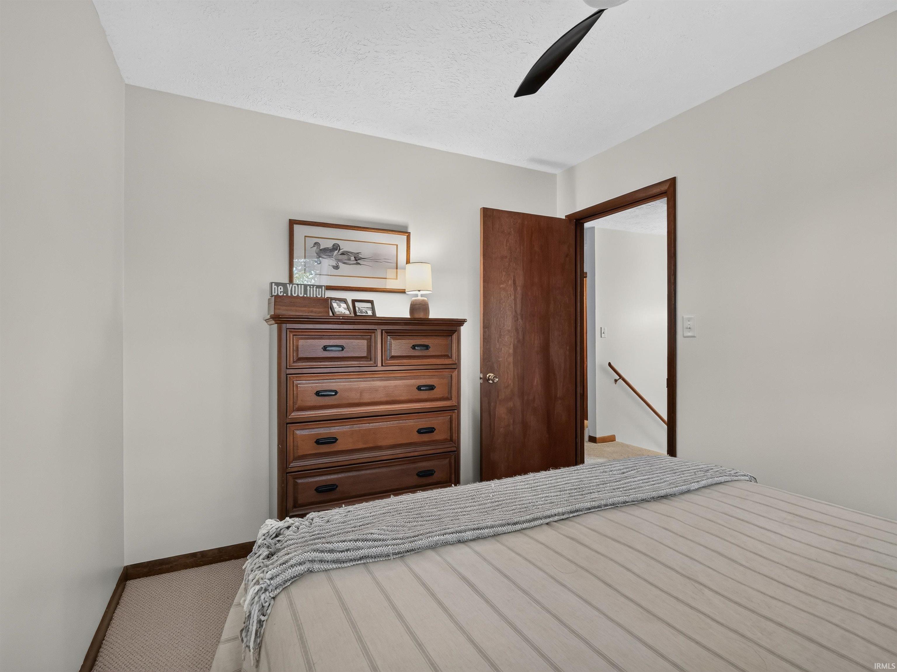 Neutral painted walls with white trim, a wood-finish door, and a ceiling fan
