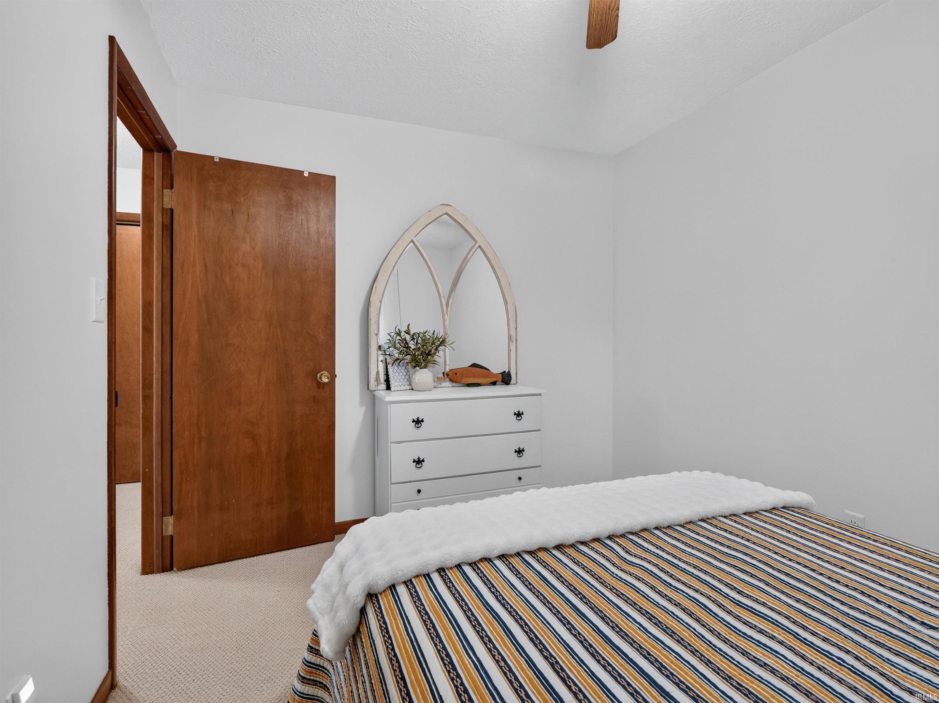 Carpeted room with a solid wood door and trim, featuring light-toned walls and a ceiling fan
