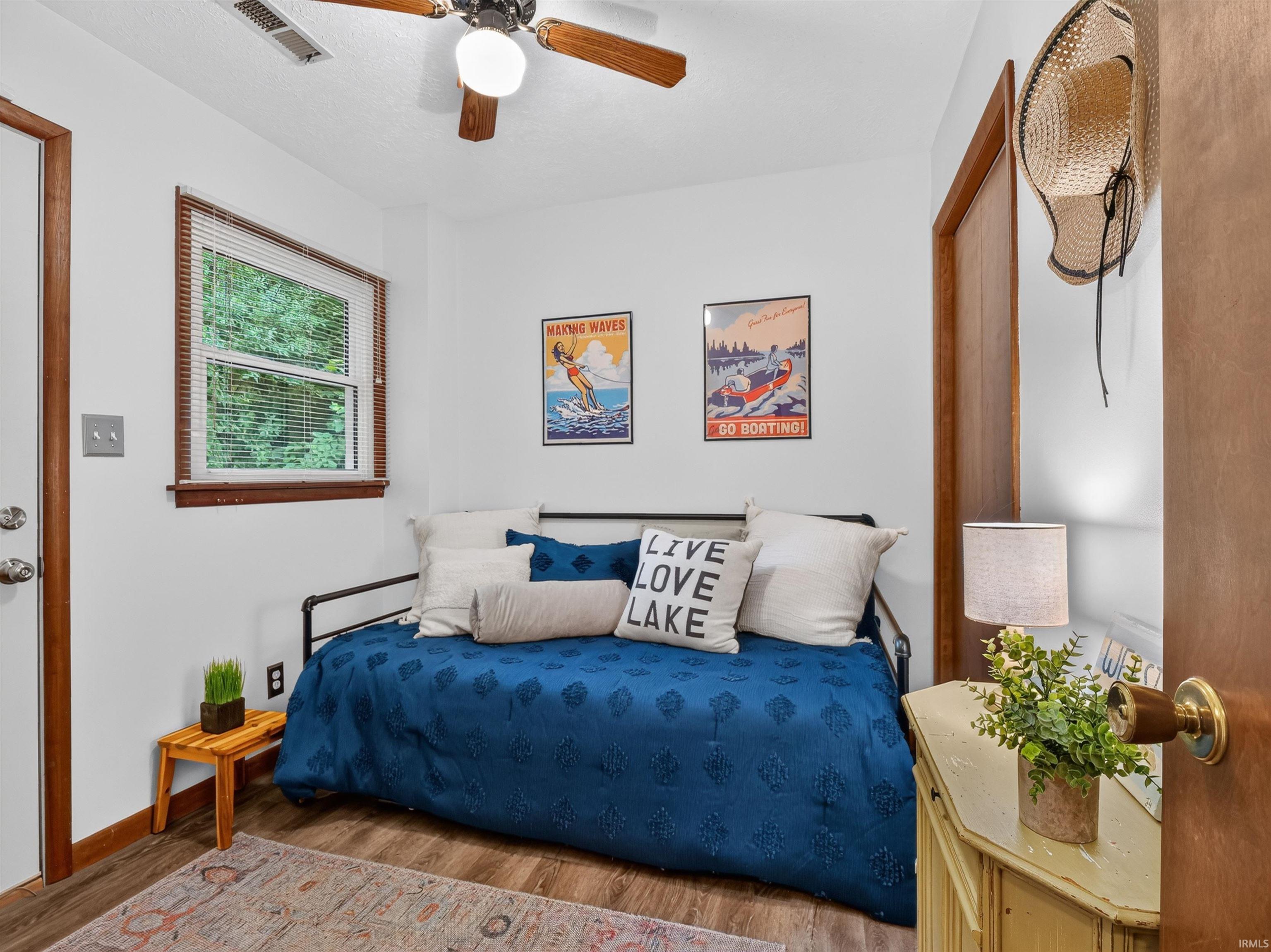 Interior room featuring wood-finish flooring, a ceiling fan with integrated lighting, and a white door with a silver knob