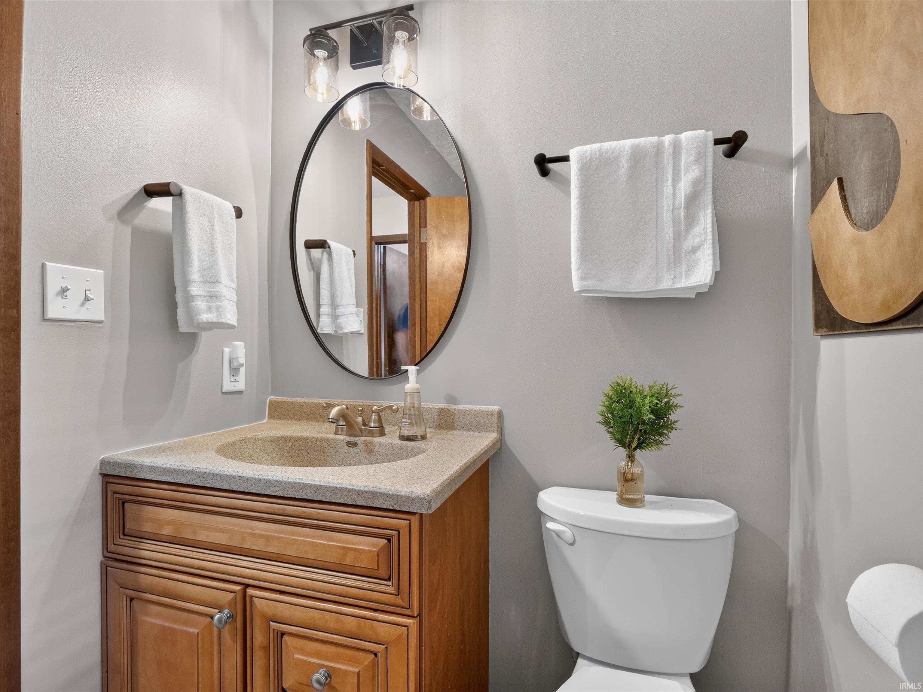 Bathroom vanity with a light-colored countertop, integrated sink, and wood-finish cabinetry