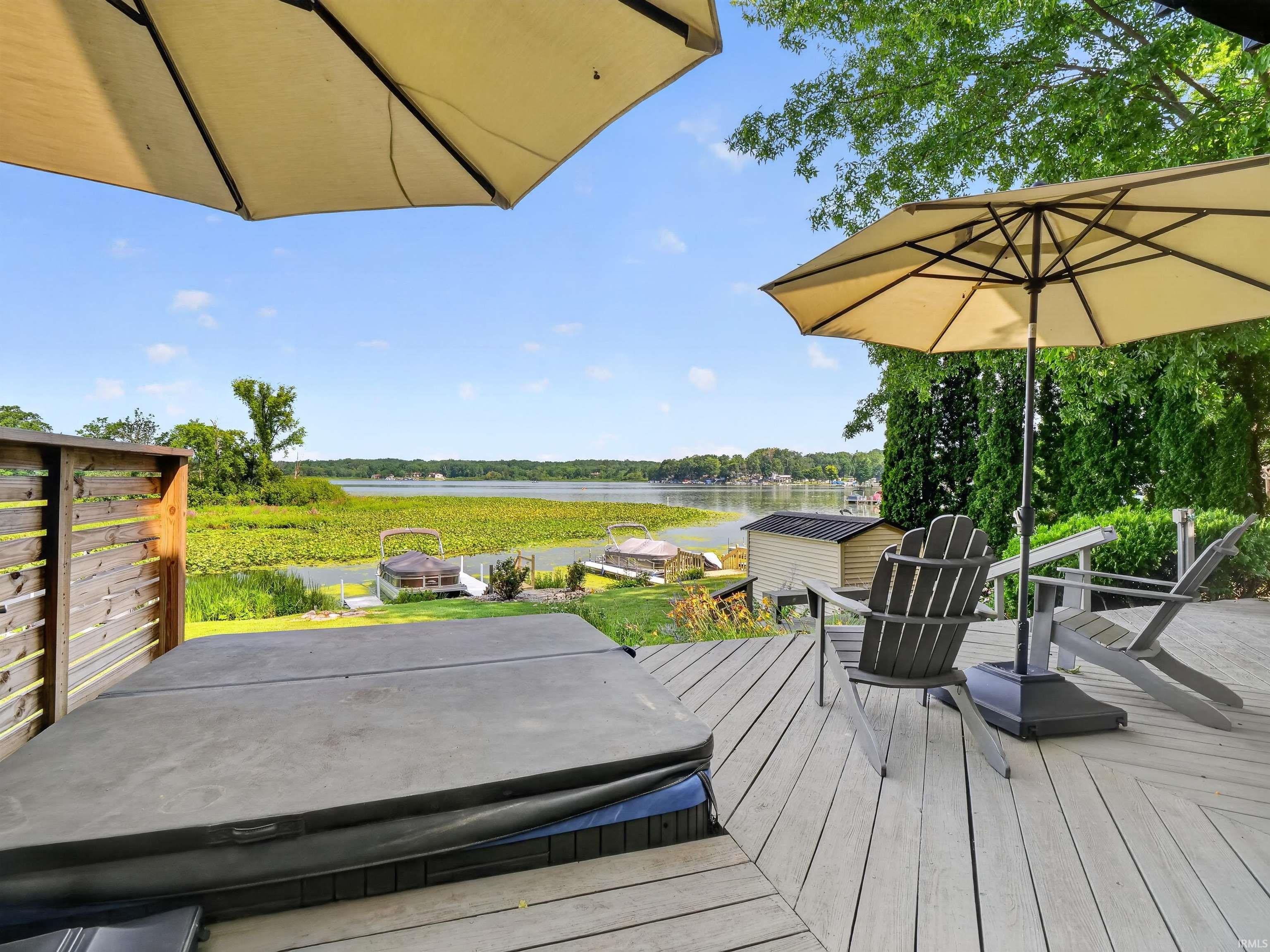 Expansive outdoor deck featuring composite decking, a hot tub, and a partial privacy fence