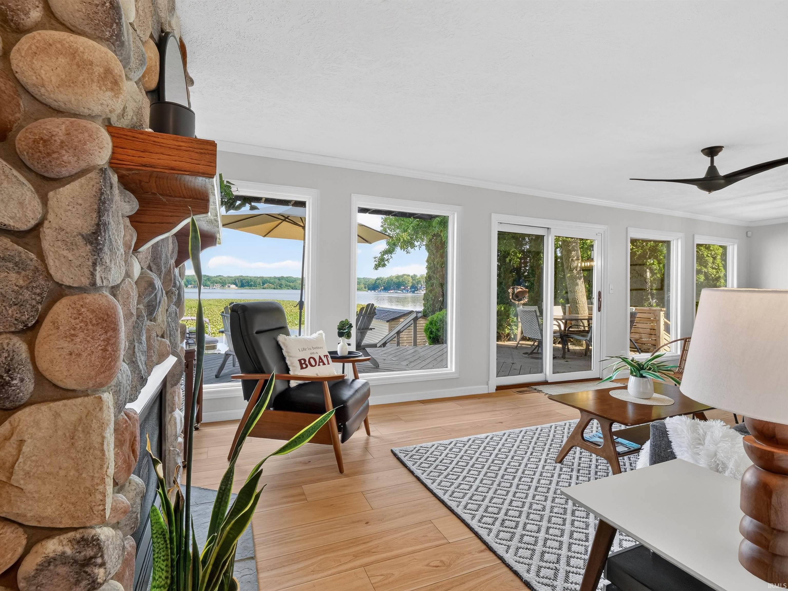 Living area with extensive window placement, wood-finish flooring, and a stone-clad fireplace