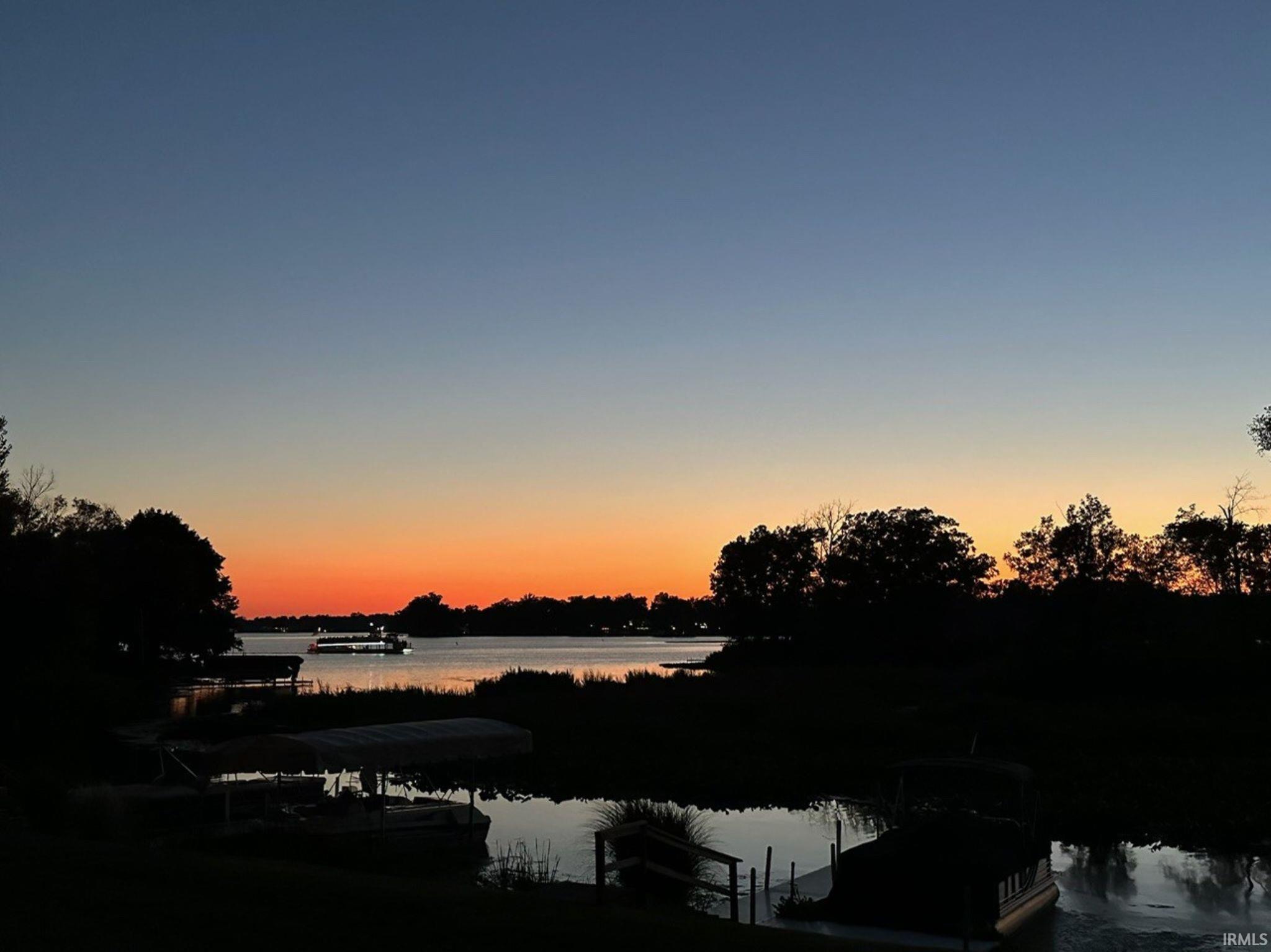 Waterfront setting featuring a private boat dock and mature trees