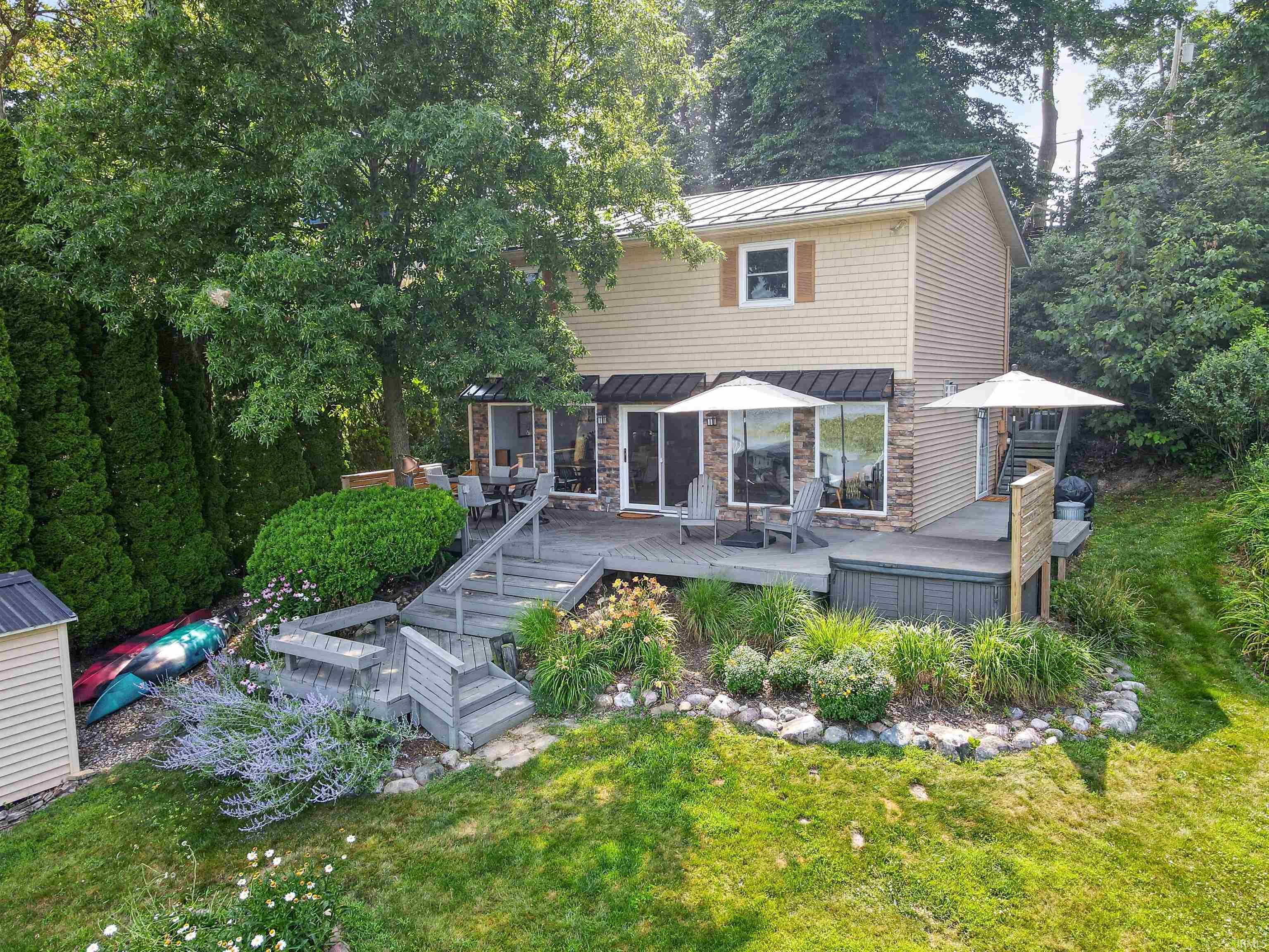 Two-story residence featuring a shingle and stone veneer facade, a metal roof, and an expansive multi-level deck