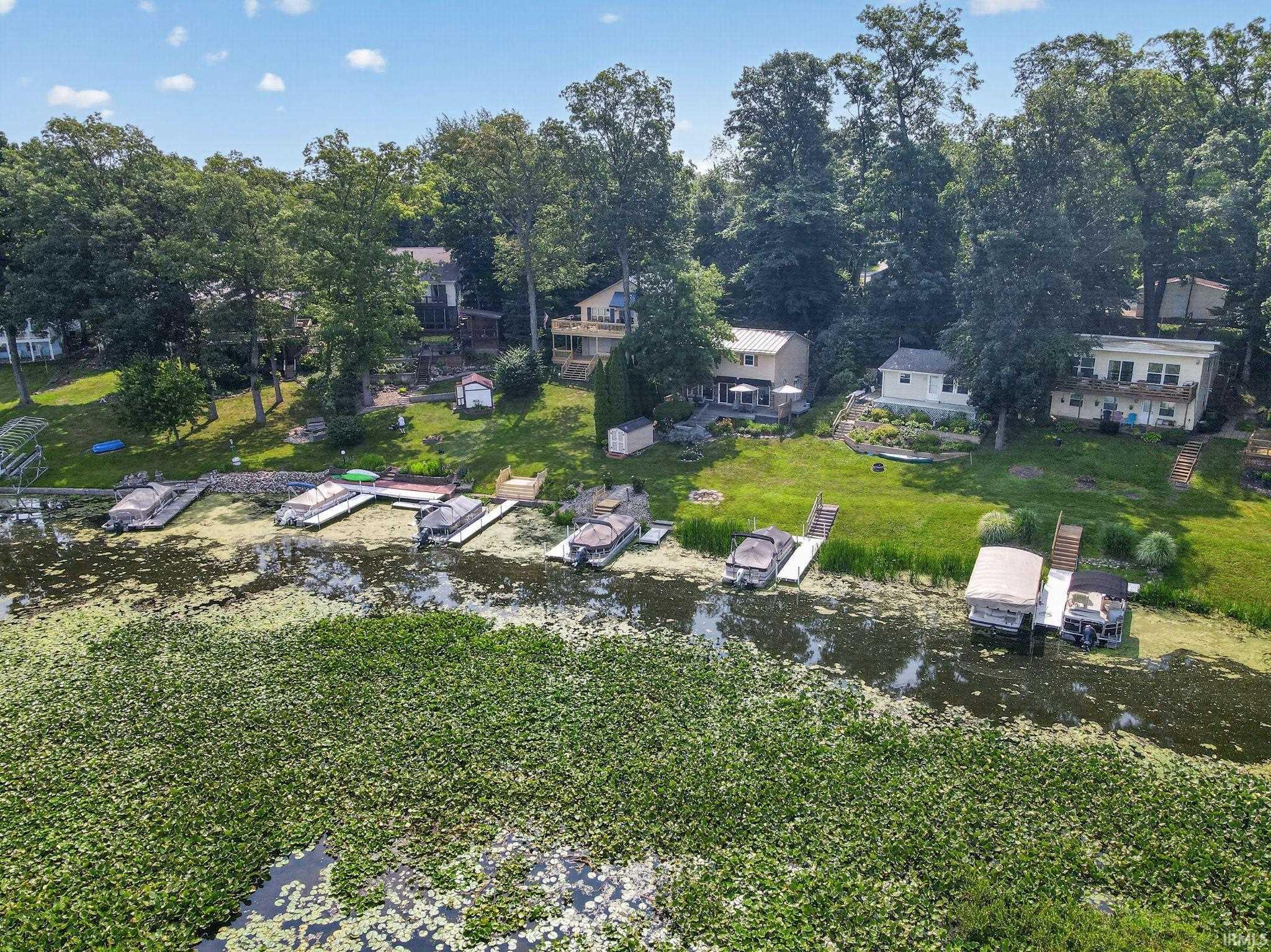 Waterfront property featuring multiple boat docks and mature trees