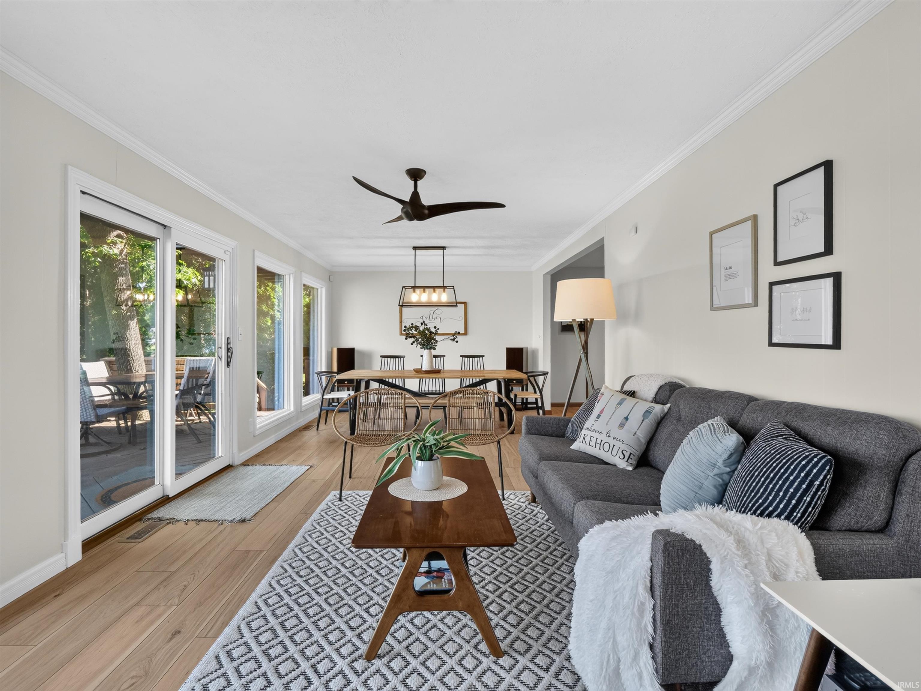 Bright living area featuring wood-finish flooring, white crown molding, and an abundance of natural light from multiple glass sliding doors