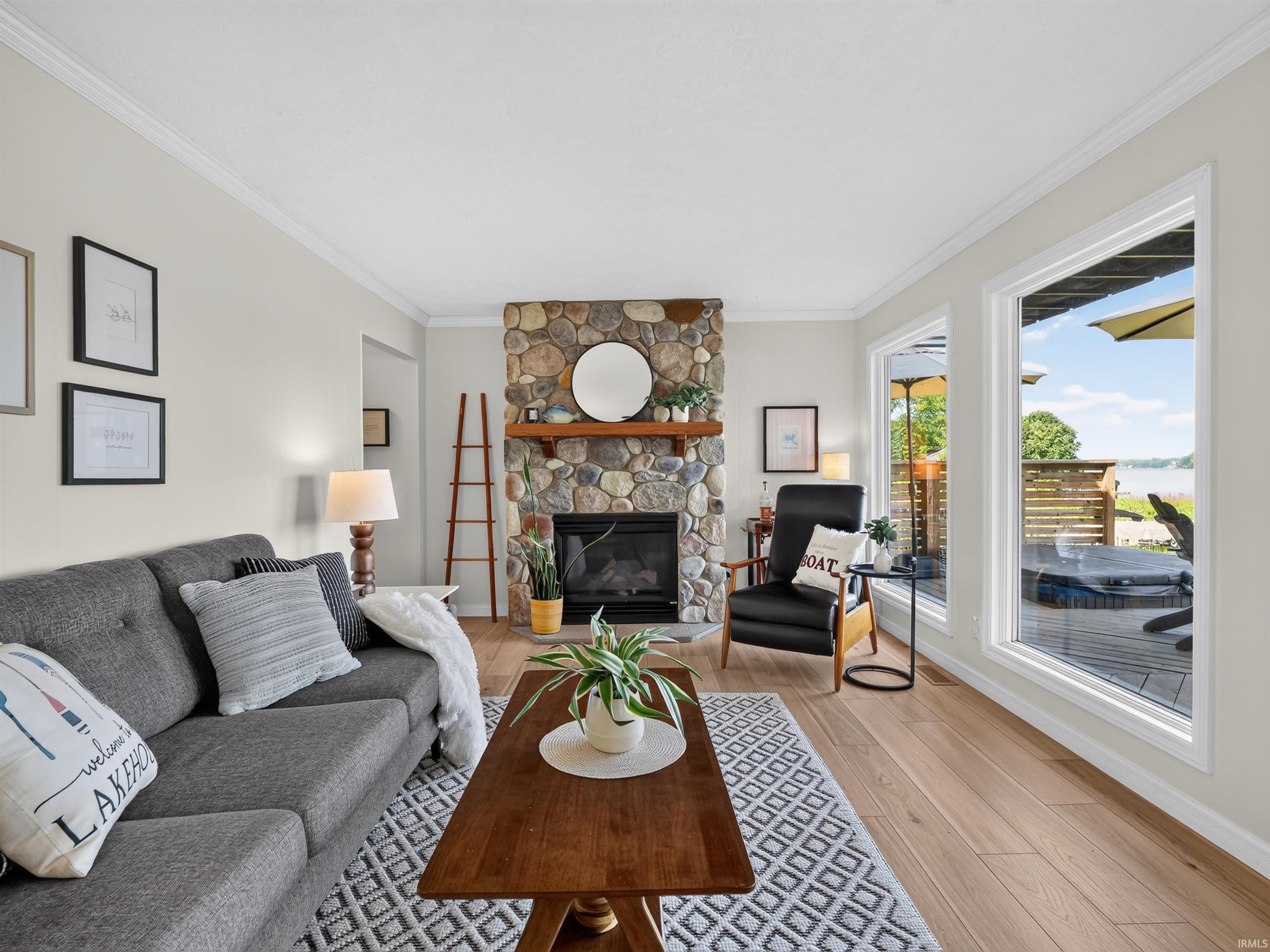 Living area featuring light wood-finish flooring and a natural stone fireplace with a wood mantel