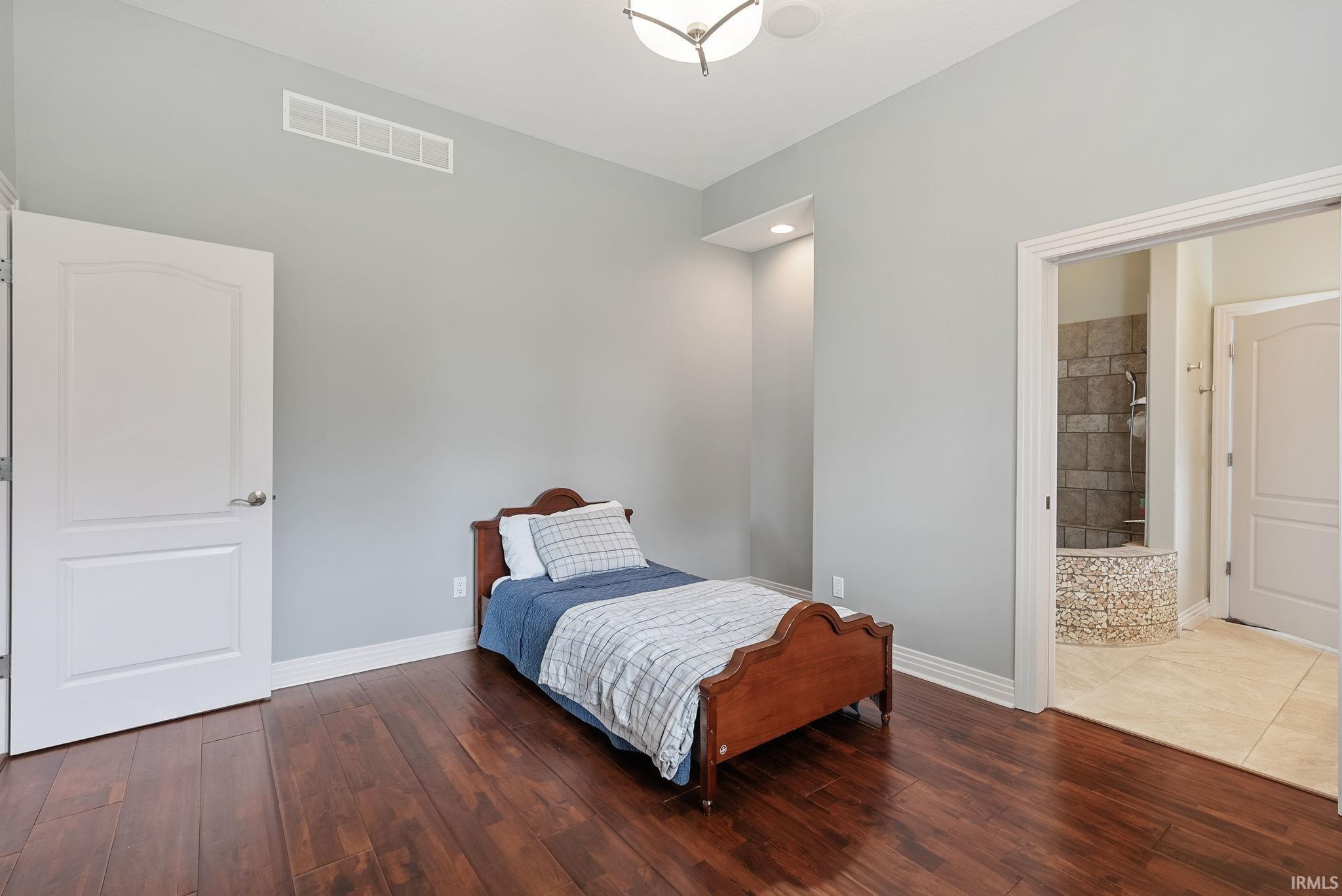 Spacious room featuring rich wood-finish flooring and light grey walls