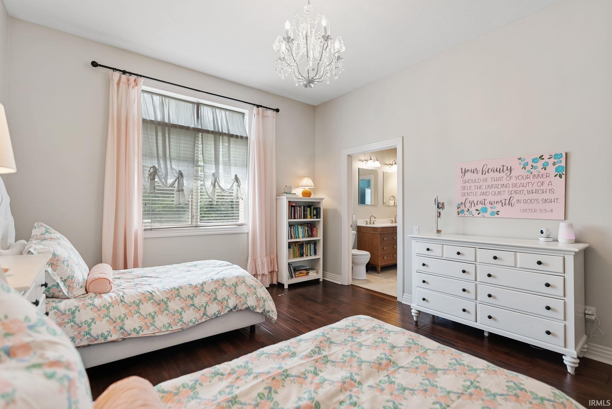 Bedroom featuring dark wood-finish flooring, a crystal chandelier, and a window with blinds and drapes