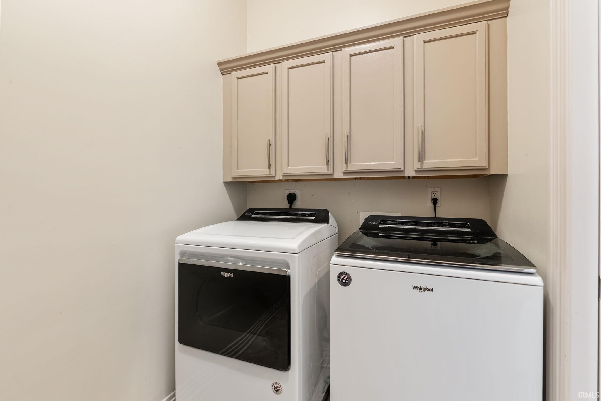 Laundry area featuring shaker-style cabinetry with crown molding, light-toned walls, and a built-in shelf