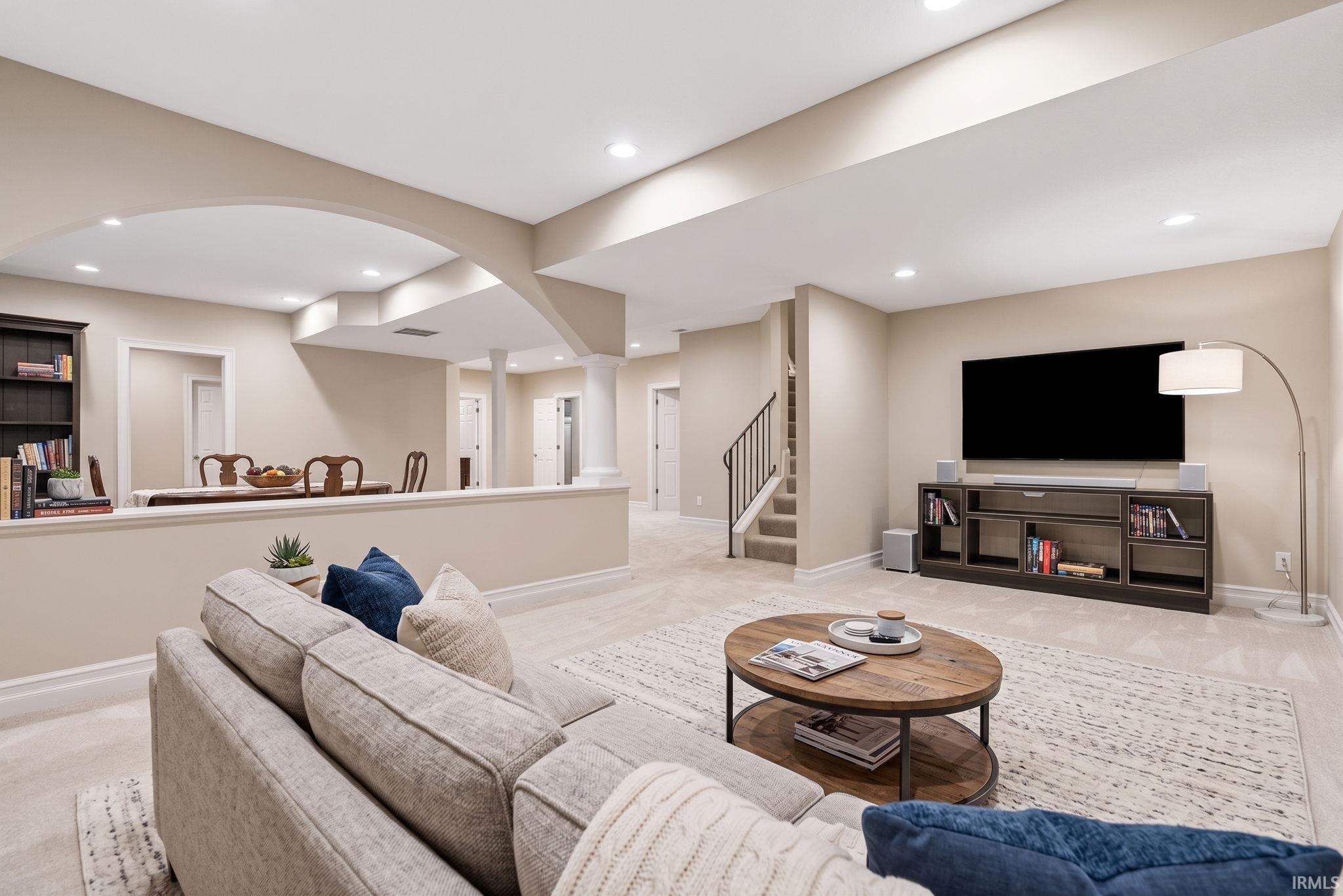 Lower-level living area featuring recessed lighting, archways, column details, and carpeted flooring