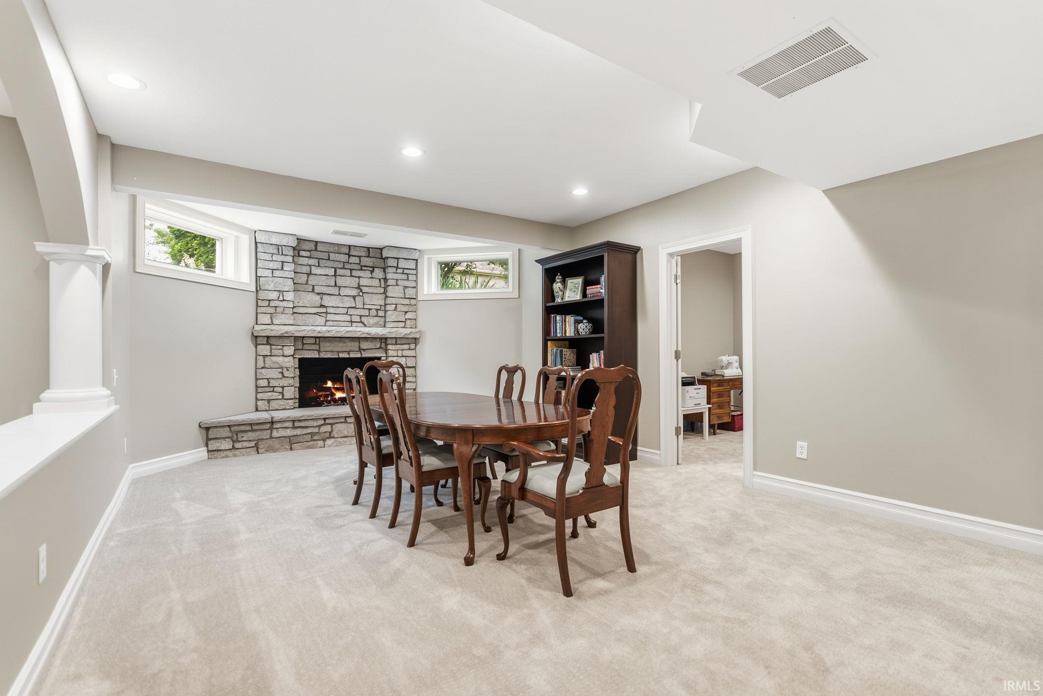 Finished lower level featuring a stone-faced fireplace, recessed lighting, neutral carpeting, and a built-in bookcase