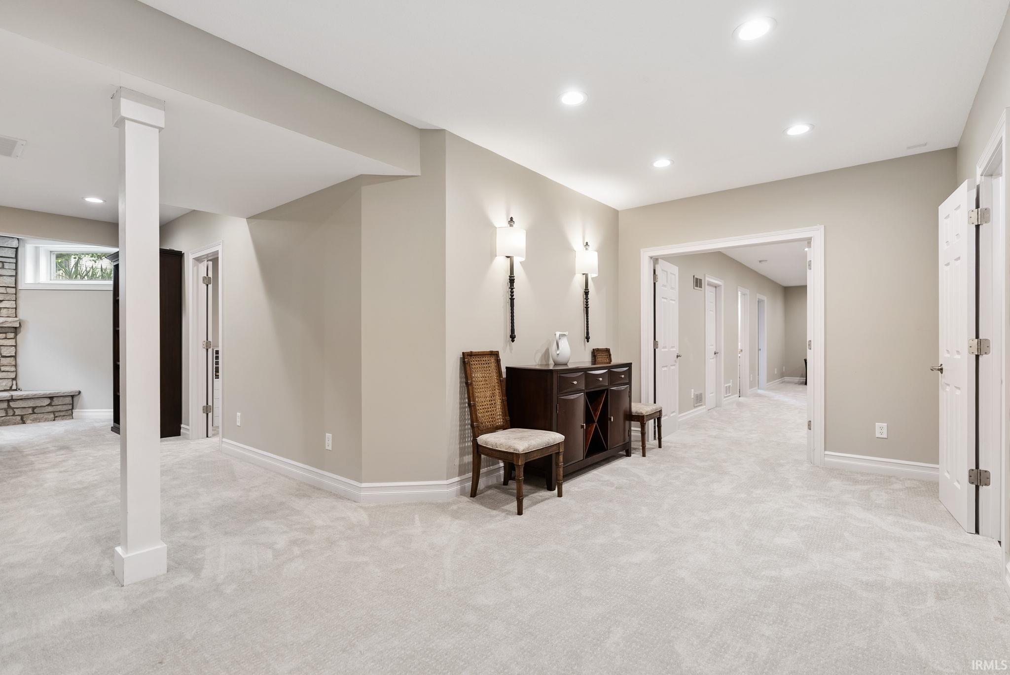 Spacious interior room featuring light-colored carpet flooring, recessed ceiling lighting, and white baseboards
