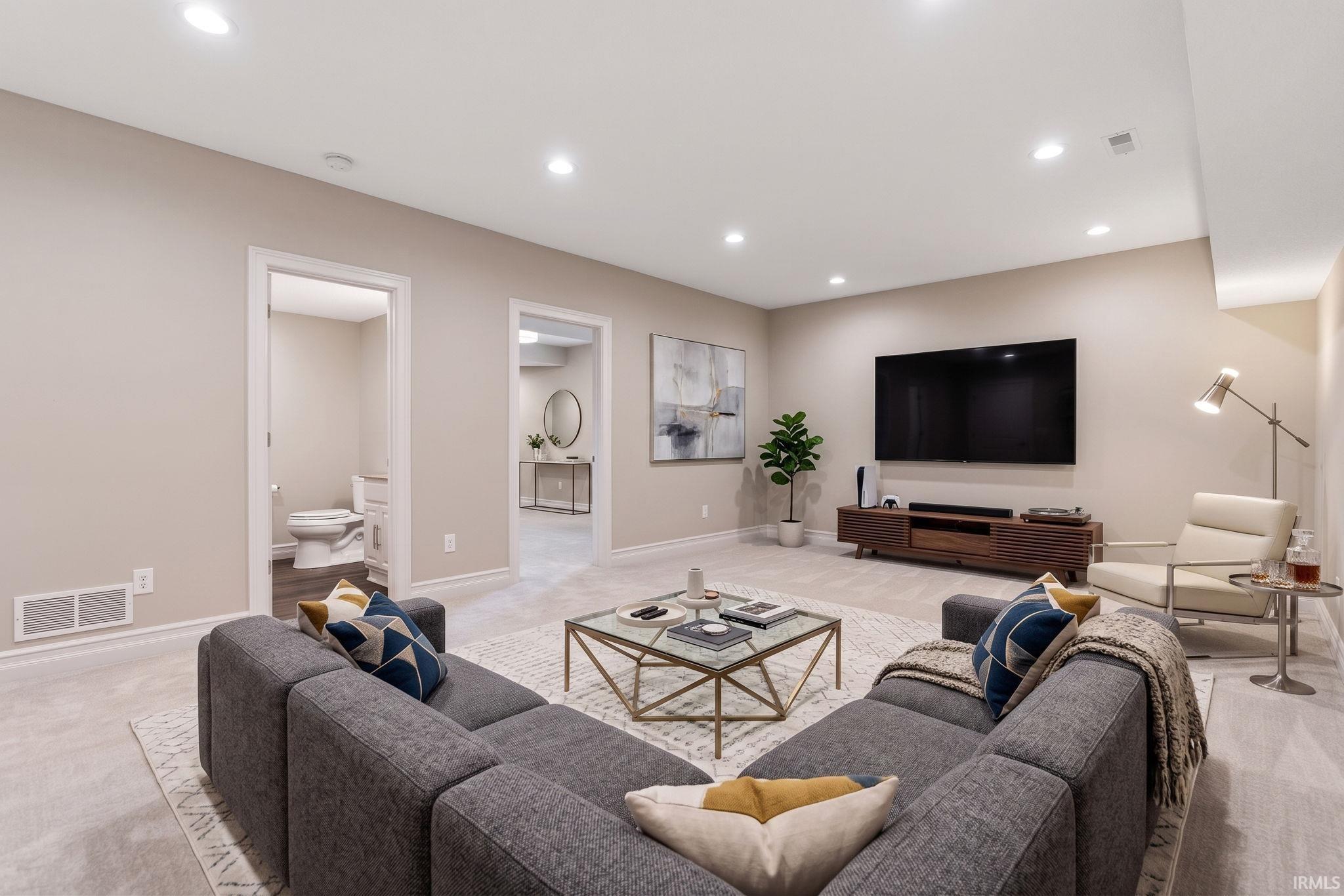 Spacious lower-level living area with recessed lighting, light-toned carpeting, and neutral wall tones
