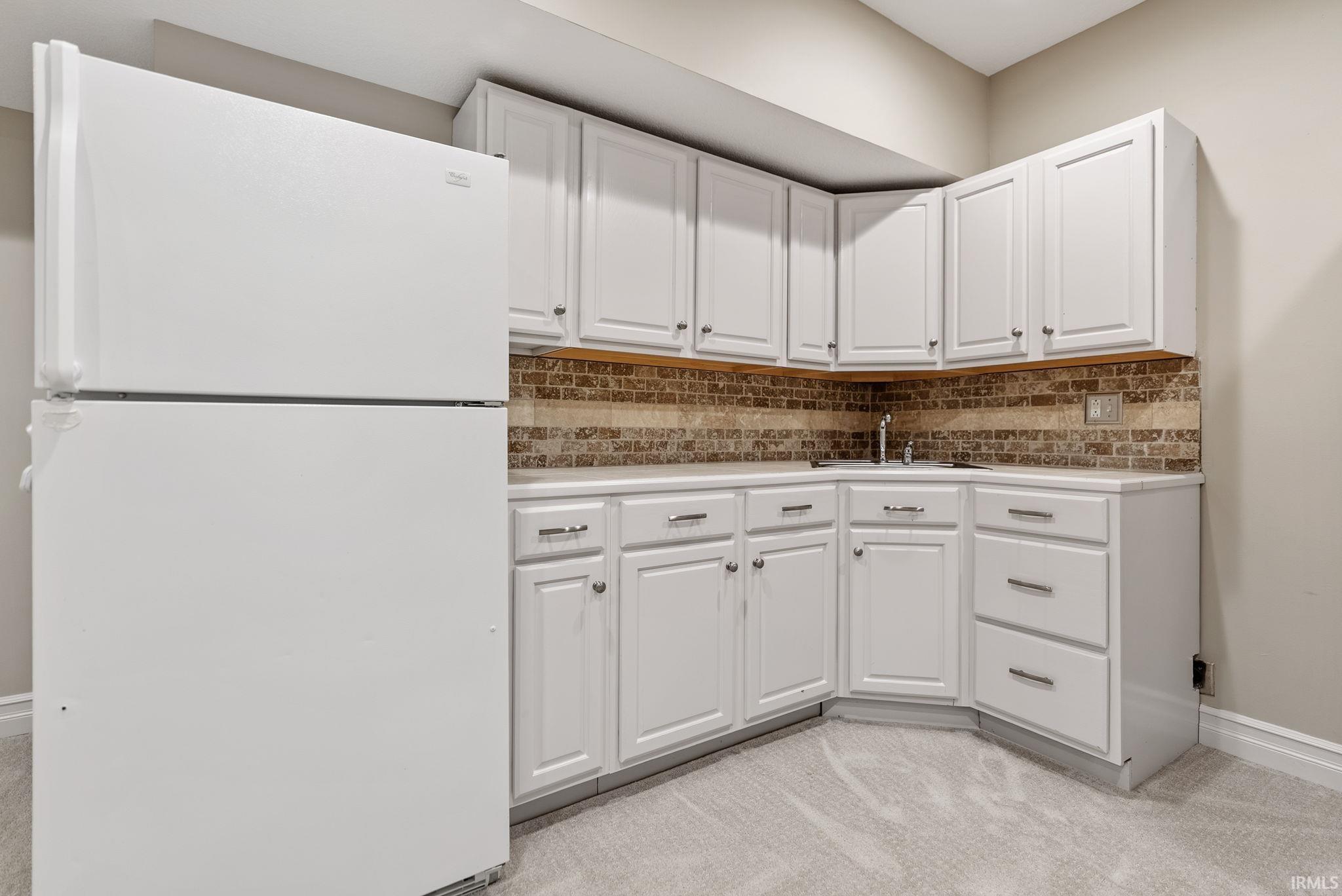 Kitchenette featuring white cabinetry, a single basin sink, and a tiled backsplash