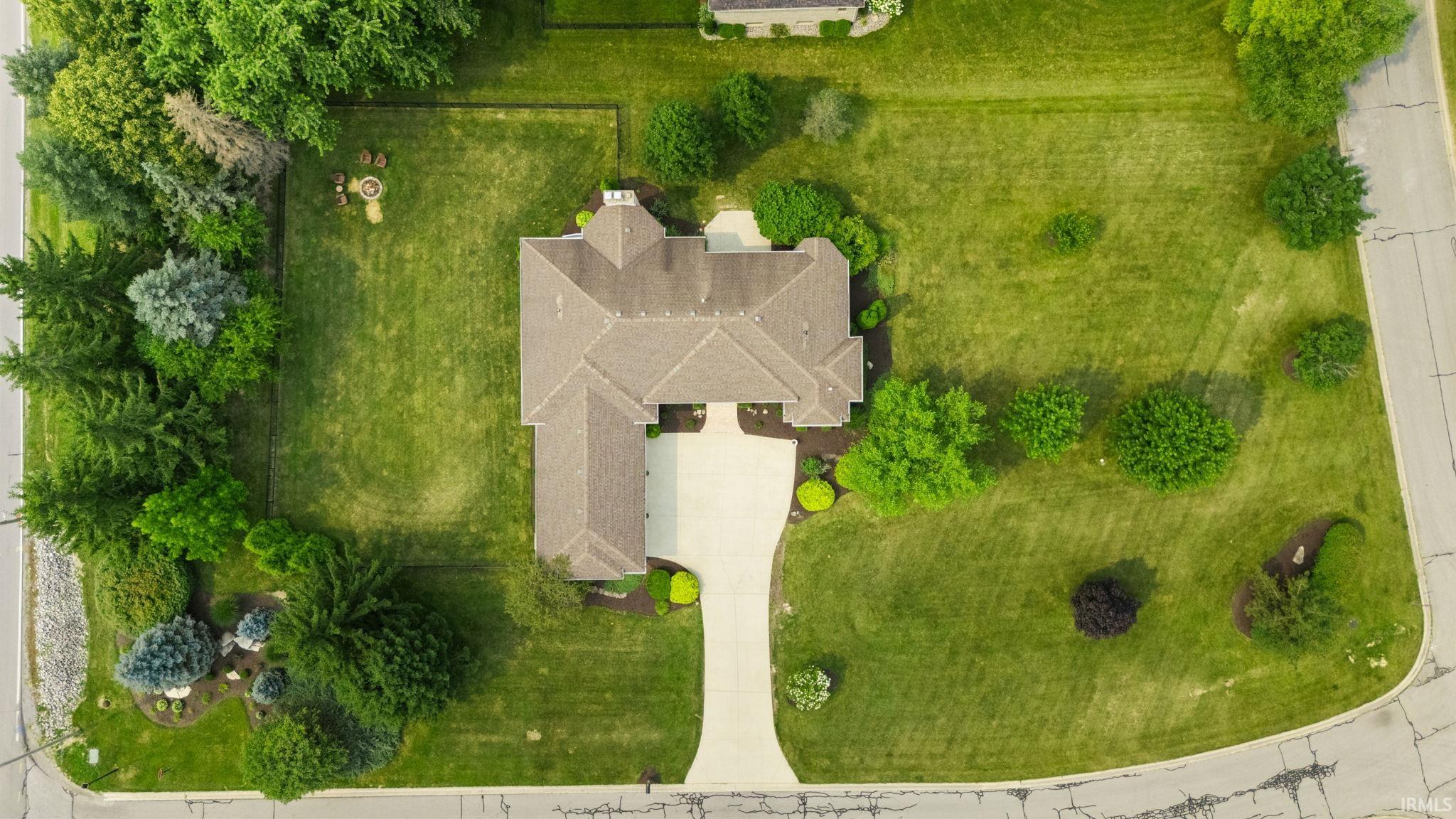 Expansive property featuring a large residence with a multi-gabled roof, extensive green lawns, mature trees, a paved driveway, and a fenced rear yard
